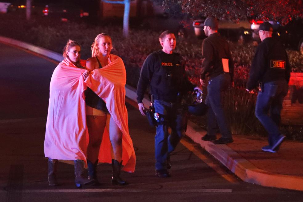 -FOTODELDIA- MAN02. THOUSAND OAKS (ESTADOS UNIDOS), 08/11/2018.- Dos mujeres envueltas en una sábana abandonan el área del tiroteo cerca del bar Borderline en la localidad de Thousand Oaks, California, Estados Unidos, hoy 8 de noviembre de 2018. Al menos 12 personas han muerto en este tiroteo perpetrado por un individuo aun sin identificar, que también ha sido encontrado muerto en el interior del bar. EFE/ Mike Nelson