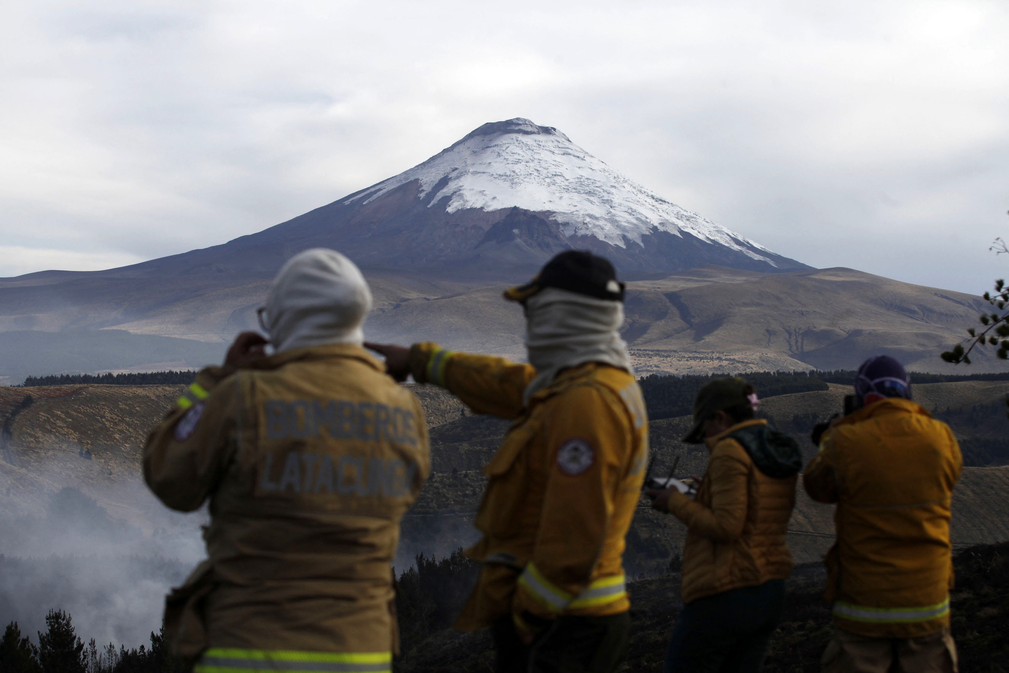 Firefighters prepare to put out a forest fire with Cotopaxi volcano in the background in Latacunga, Cotopaxi Province, Ecuador, on September 27, 2024.