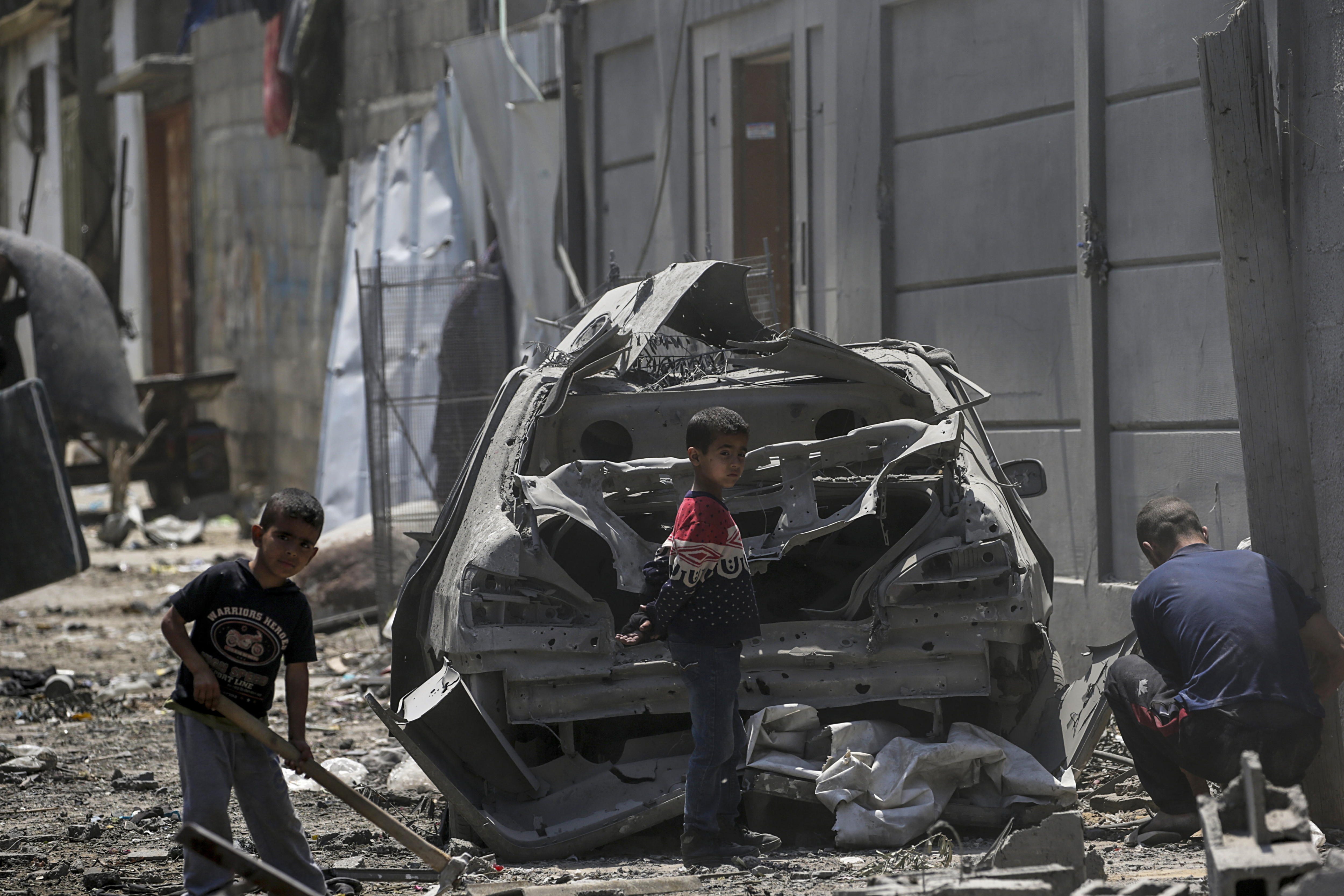 Maghazi Camp (-), 15/04/2024.- A Palestinian man with two children among destroyed buildings near a damaged car in Al Maghazi refugee camp, central Gaza Strip, 15 April 2024, following Israeli air strikes. More than 33,700 Palestinians and over 1,450 Israelis have been killed, according to the Palestinian Health Ministry and the Israel Defense Forces (IDF), since Hamas militants launched an attack against Israel from the Gaza Strip on 07 October 2023, and the Israeli operations in Gaza and the West Bank which followed it. EFE/EPA/MOHAMMED SABER