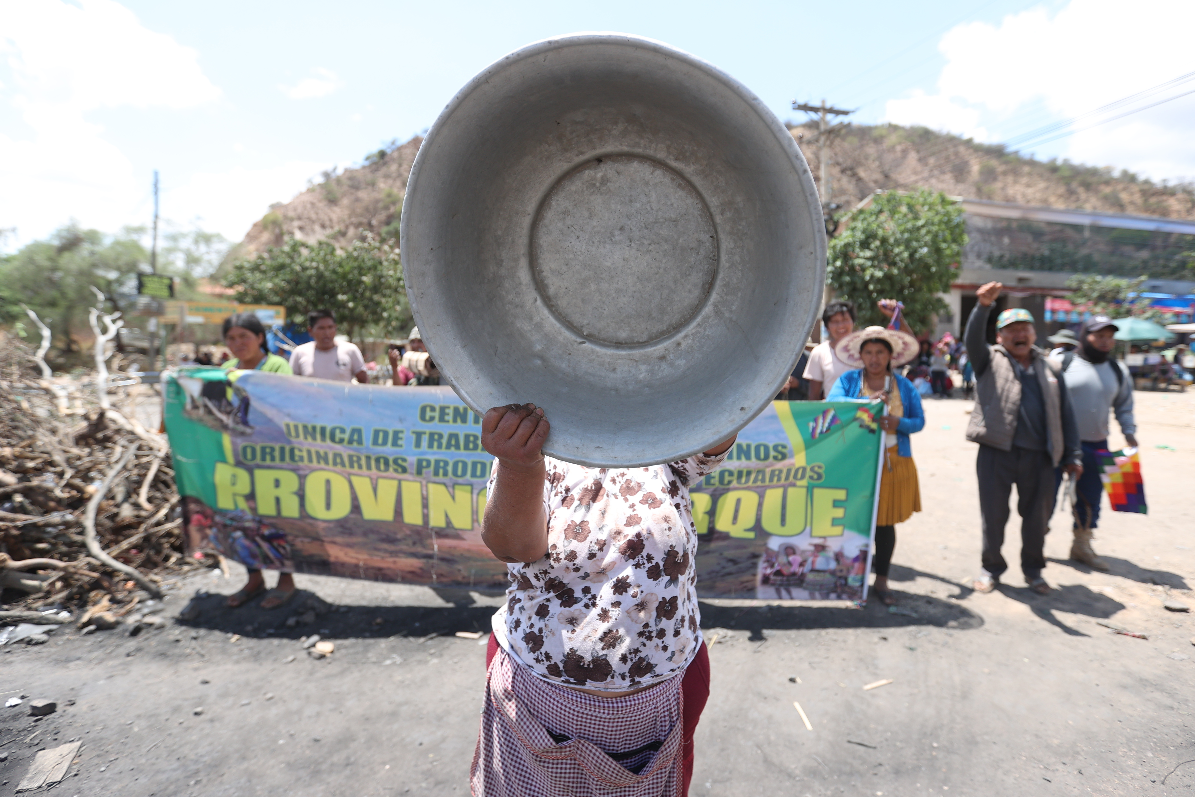 -FOTODELDÍA- AME2623. PAROTANI (BOLIVIA), 29/10/2024.- Una seguidora del expresidente de Bolivia, Evo Morales, golpea un tazón metálico en una marcha este martes, por una vía bloqueada en Parotani (Bolivia). Seguidores de Morales mantienen desde hace 16 días un bloqueo de caminos para que se retiren los procesos judiciales por estupro y trata de personas contra el exgobernante, junto a exigencias por la solución a la situación económica y la defensa de la candidatura presidencial del líder oficialista para 2025. EFE/ Luis Gandarillas