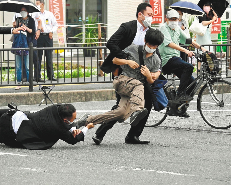 Esta imagen, obtenida del periódico Asahi Shimbun, muestra a un hombre (centro, der.), sospechoso de disparar al ex primer ministro japonés Shinzo Abe, siendo derribado al suelo por la policía en la estación Yamato Saidaiji de Nara el 8 de julio de 2022. Abe fue declarado muerto el 8 de julio, según confirmó el hospital que lo atendía, tras recibir un disparo en un acto de campaña en Nara.