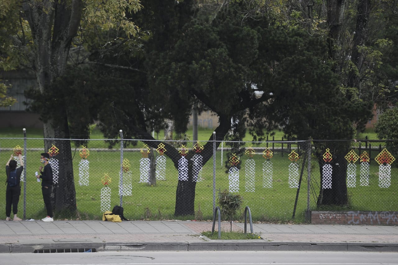 Dos personas hablando al frente de una reja en la que tejieron velas