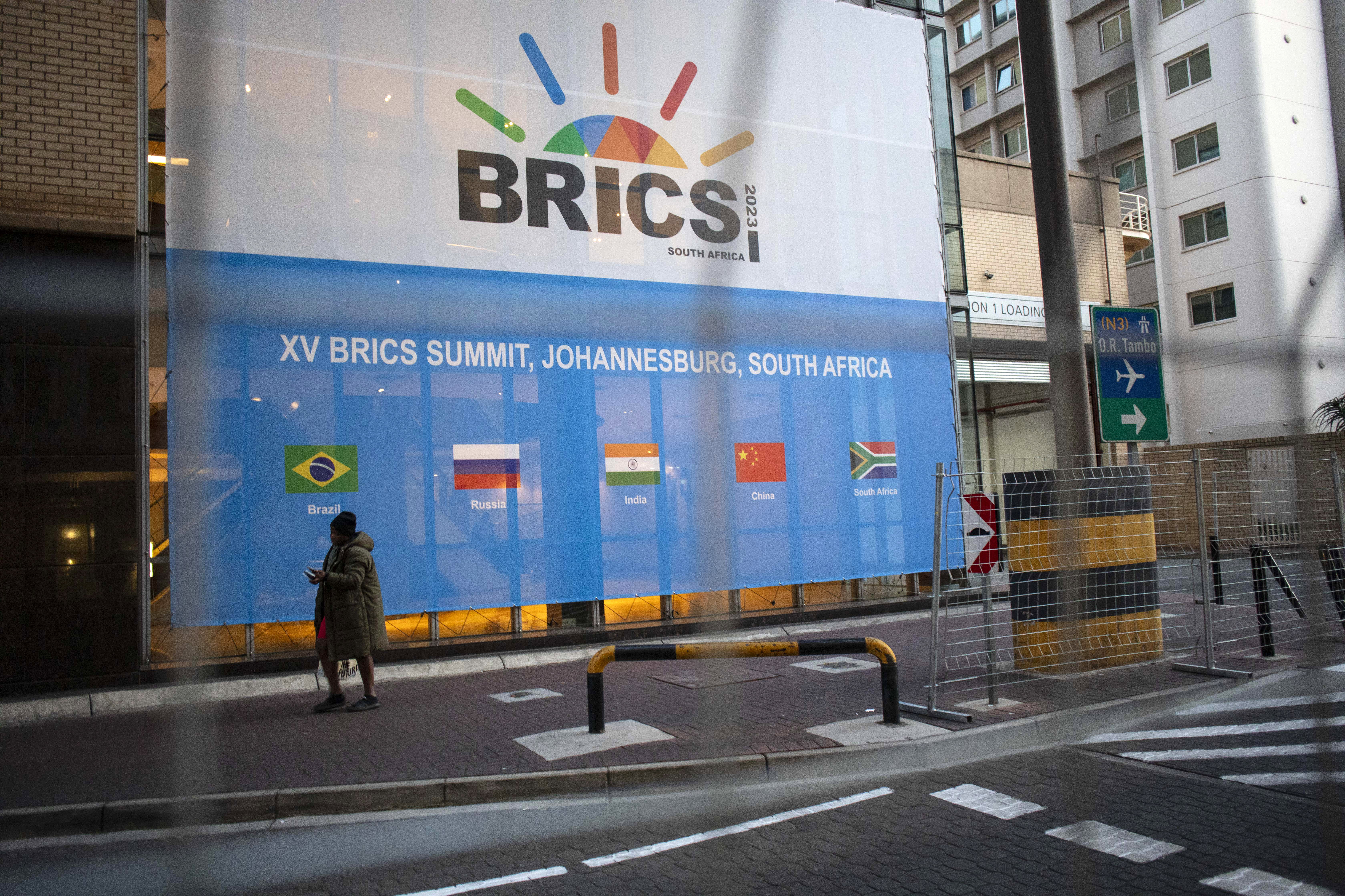 Johannesburg (South Africa), 21/08/2023.- A man walks past a banner as final preparations are underway for the 15th BRICS Summit at the Sandton Convention Centre, Johannesburg, South Africa, 21 August 2023. The security measures have been extremely high as numerous heads of state will take part in the summit. South Africa is hosting the 15th BRICS Summit, which takes place between 22-24 August, where the emerging economies of Brazil, Russia, India and South Africa, and China will attend. The Russian president will not attend the summit. (Brasil, Rusia, Sudáfrica, Johannesburgo) EFE/EPA/KIM LUDBROOK