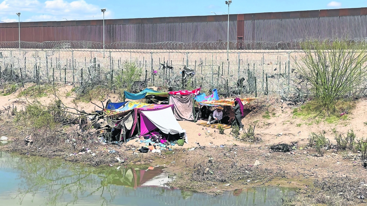 Migrantes se instalan en  campamento frente al muro