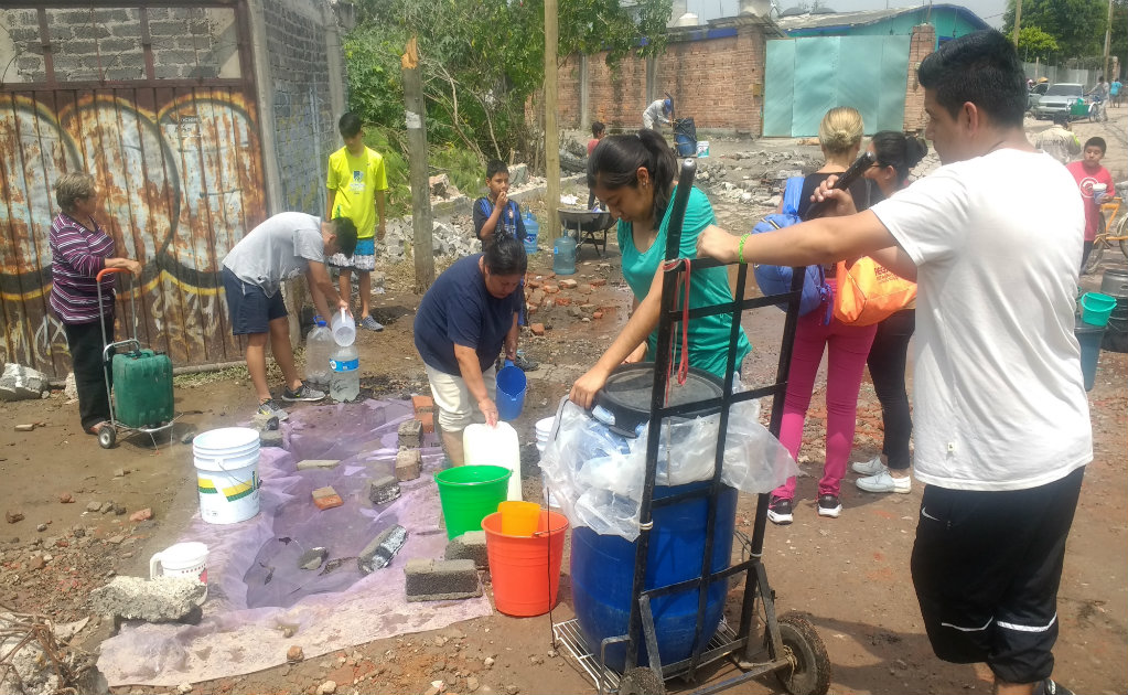 Con cubetas y jarras, vecinos de Xochimilco se abastecen de agua en fuga