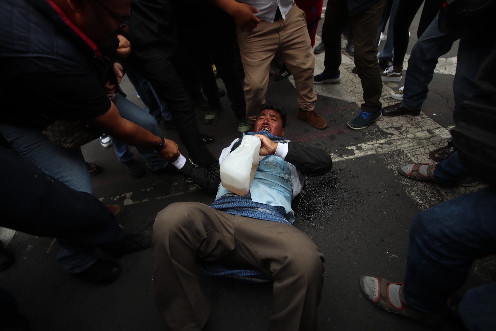 Grupo de Triquis protesta con bidones de gasolina en el Zócalo; uno de ellos intenta prenderse fuego