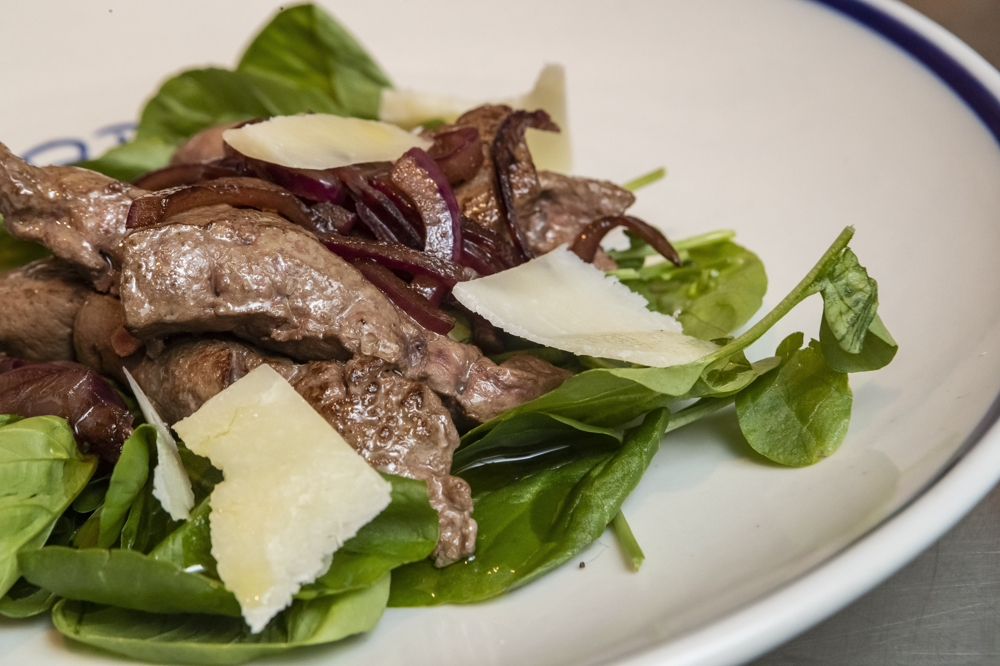 pedaços de fígado frito com cebola, folhas frescas de saladas