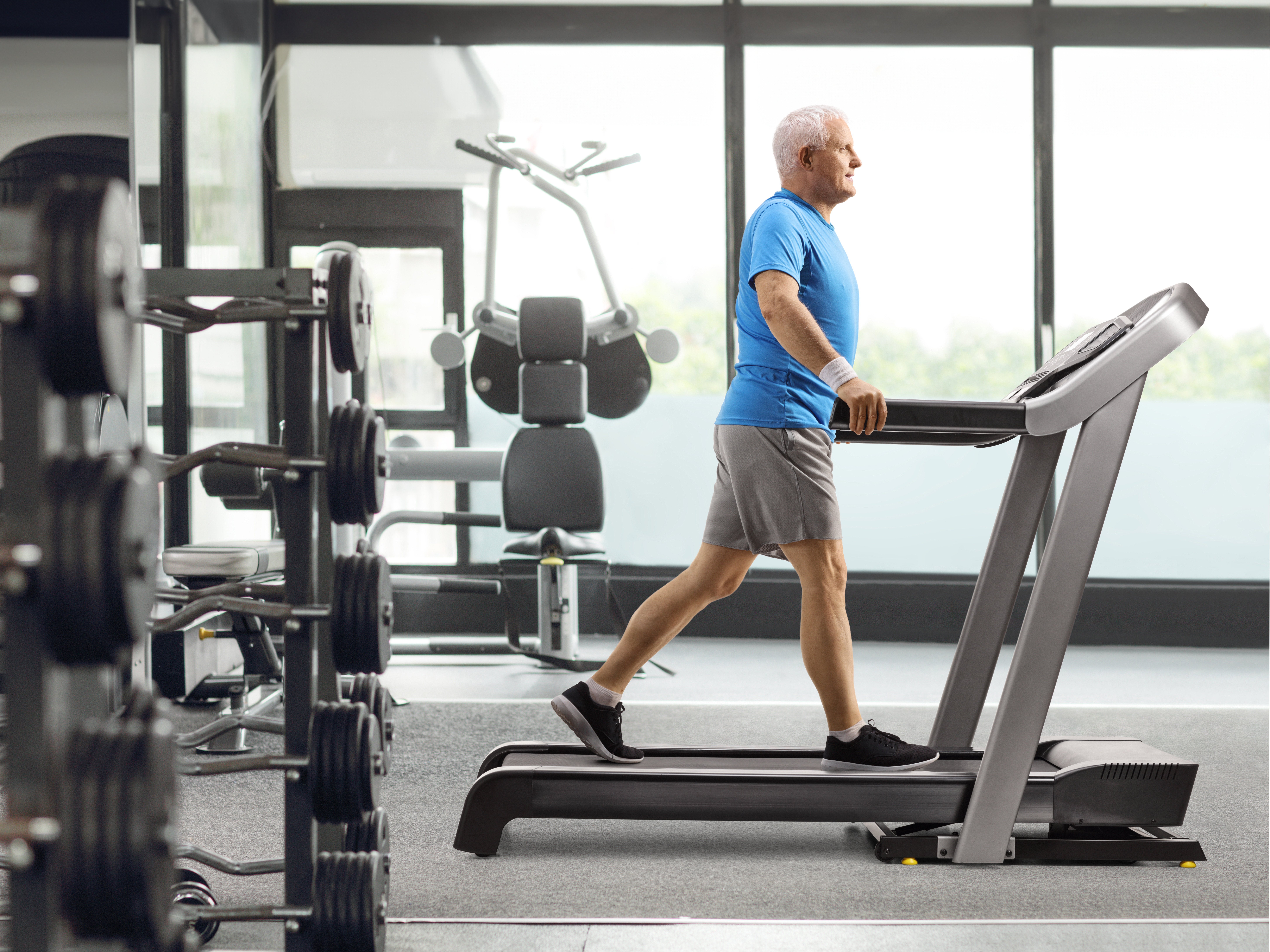 Older man walking steadily on a treadmill