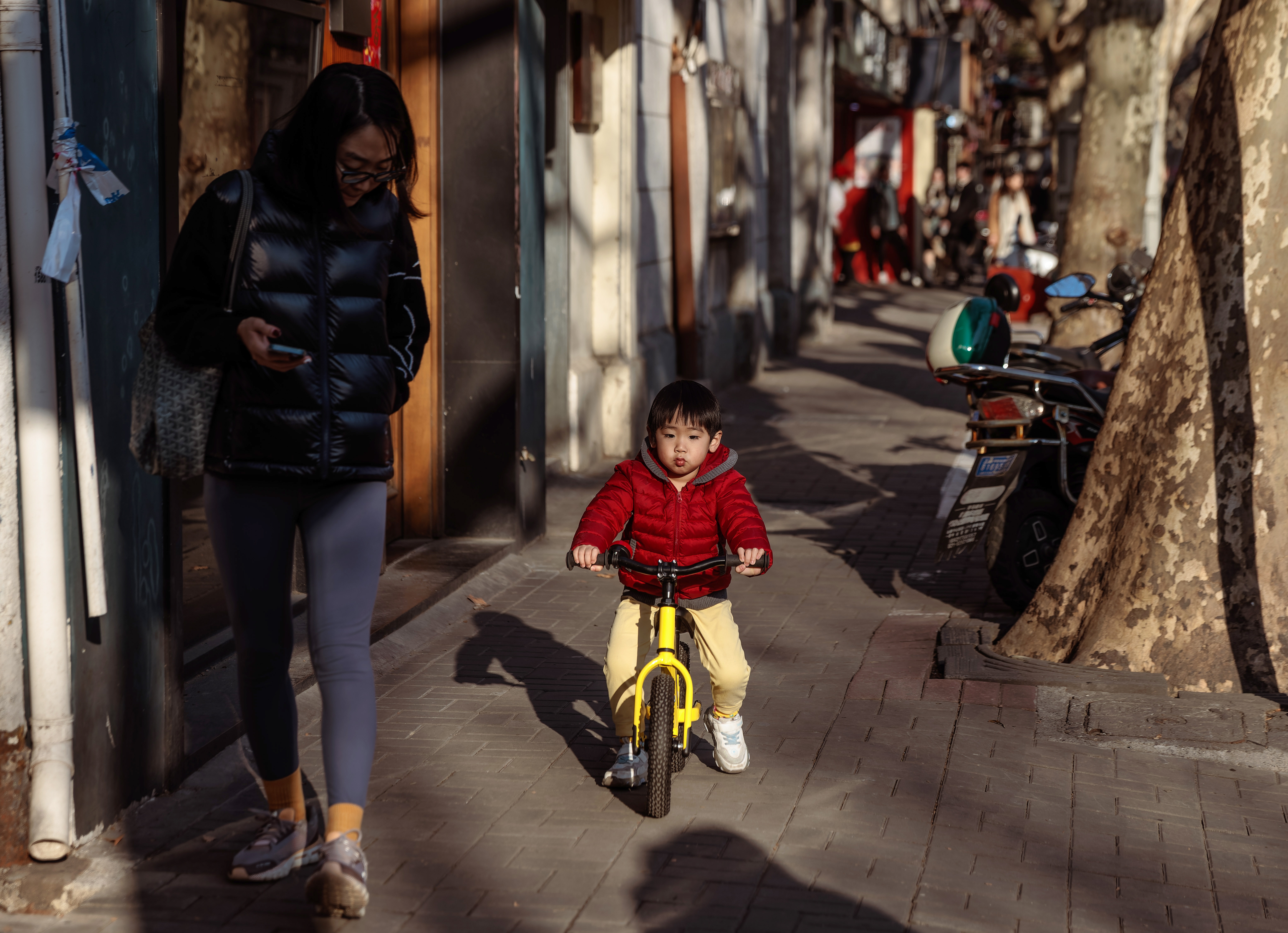 Mãe e filho andam por rua de Xangai; nova política na Província de Sichuan procura conter queda de natalidade no país