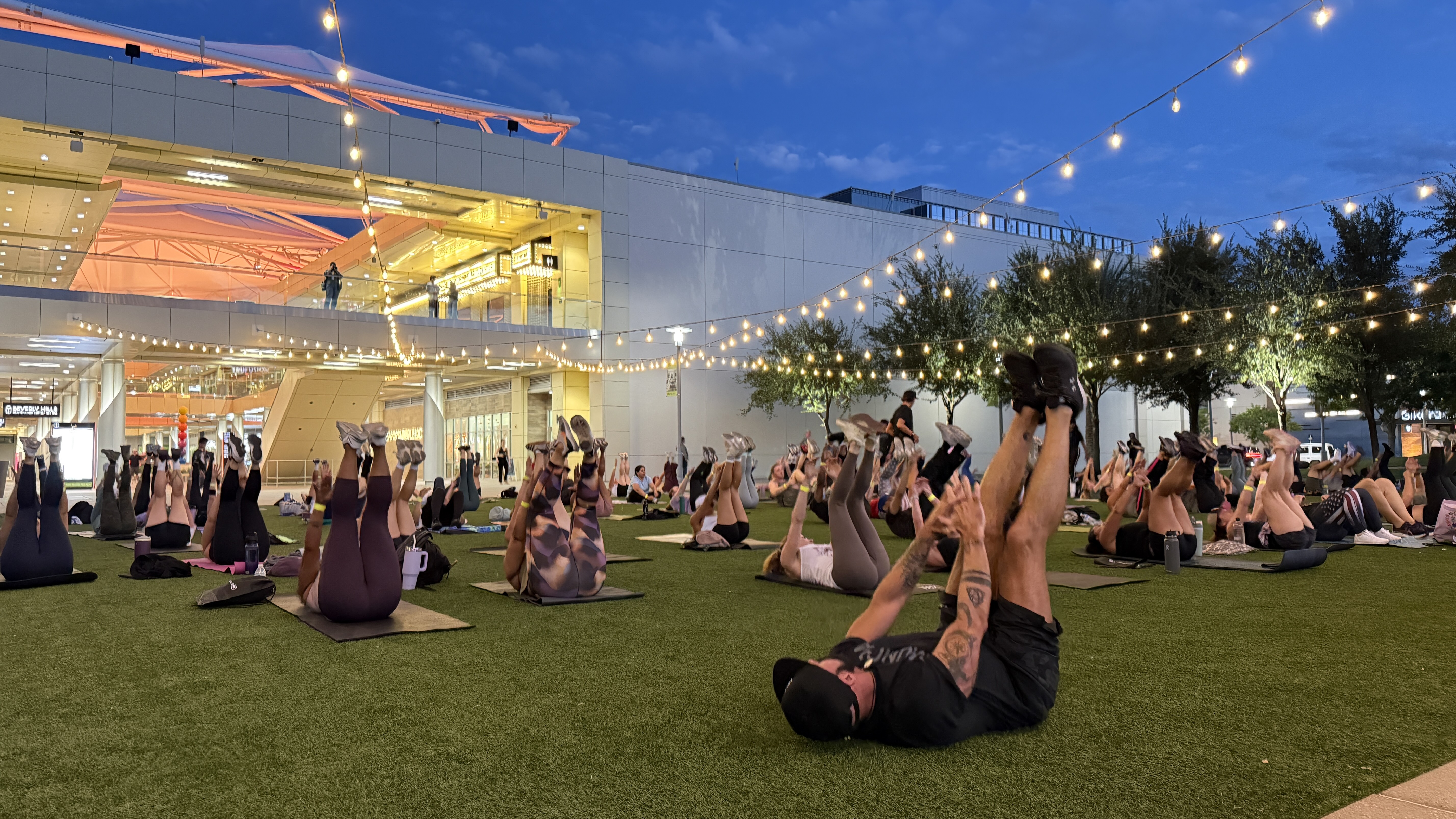 Dozens of people on exercise mats under string lights during Municipal Gym's free pre-opening workout on The Lawn at Downtown Summerlin on Oct. 20, 2026 (image: FOX5 Vegas)