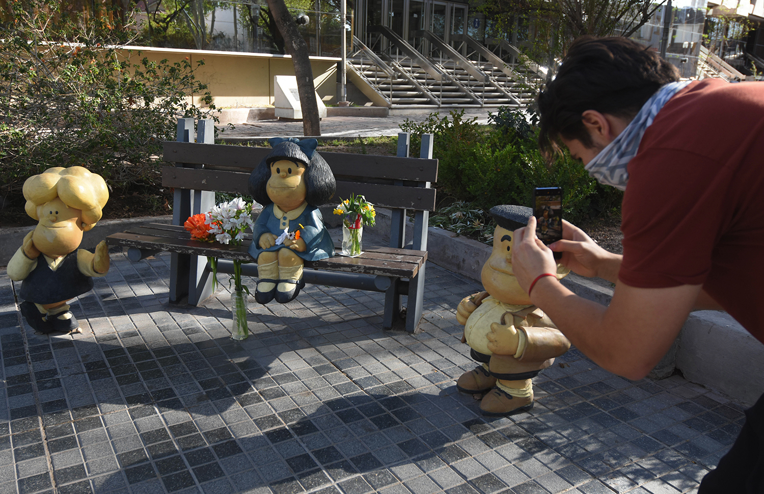 Un joven saca fotos a las esculturas de los personajes creados por Quino.