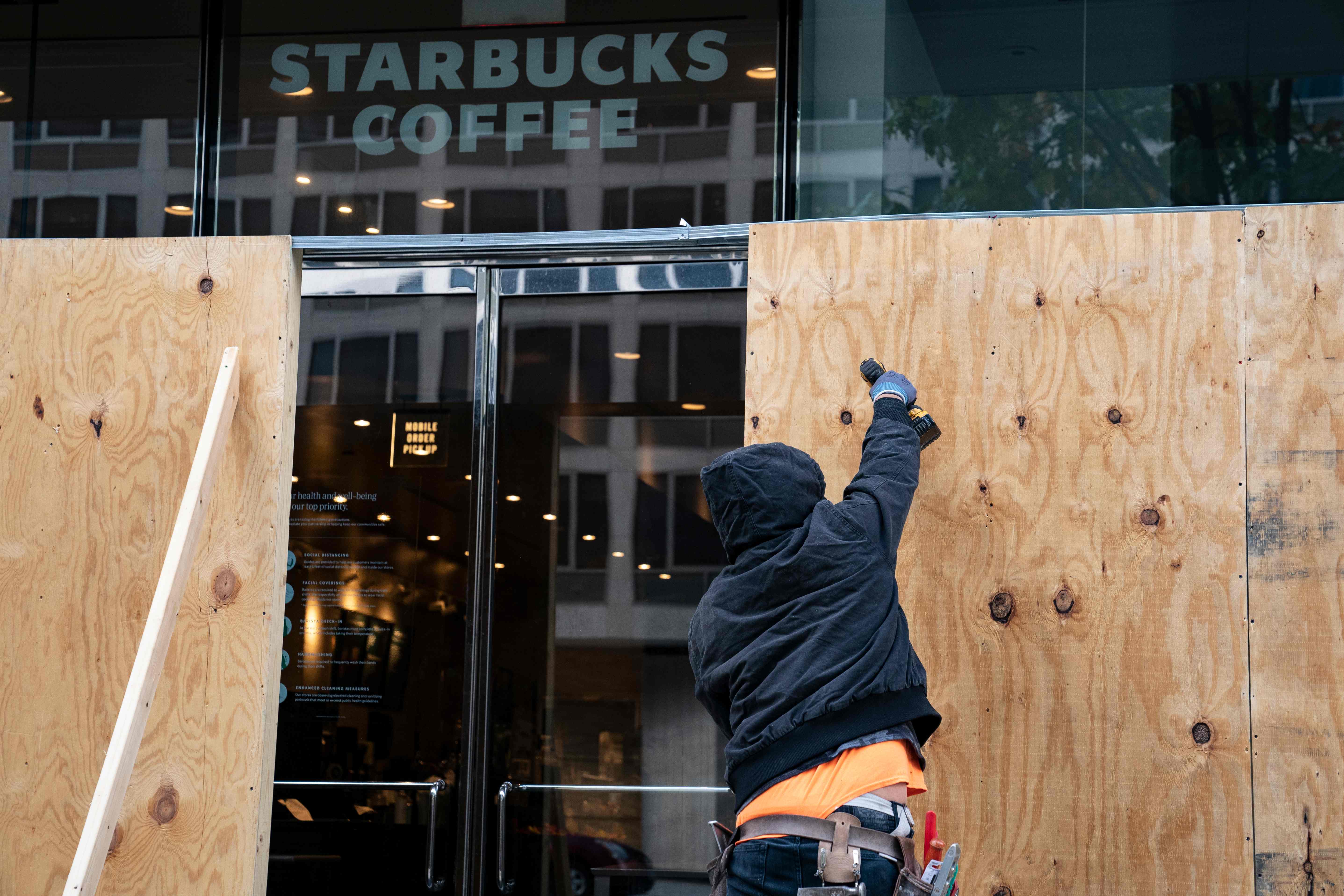 Wooden boards protect a Starbucks location near the White House on October 31, 2020 in Washington, DC. Many Washington businesses are boarding up windows in preparation for possible election related violence. - Violence erupted on January 20, 2017, in Washington, DC, as protesters damaged storefronts, and threw rocks and bricks at police officers during the inauguration of US President Donald Trump. (Photo by Alex Edelman / AFP)