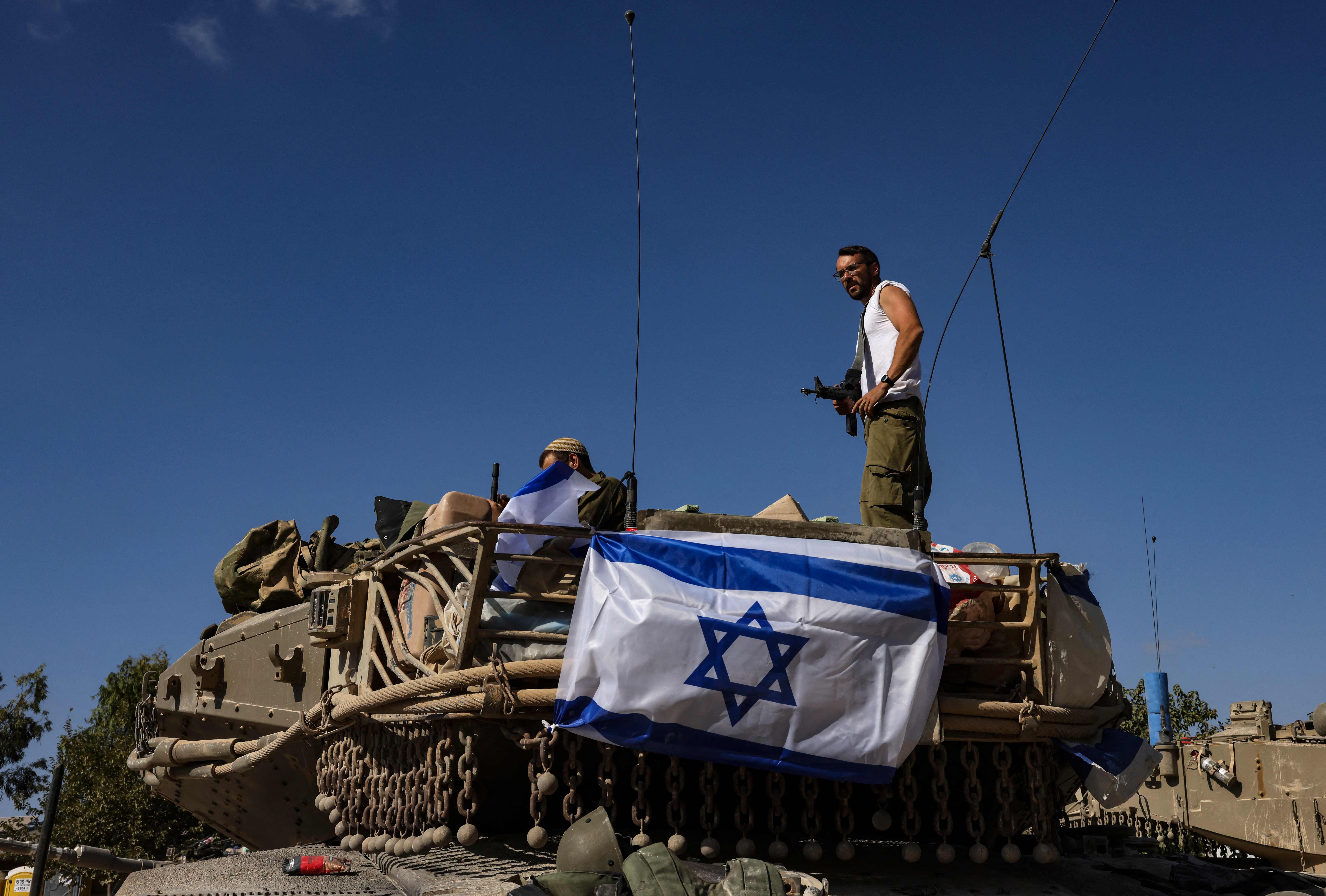 An Israeli soldier stands on top of a Merkava tank positioned outside Kibbutz Beeri near the border with the Gaza Strip on October 20, 2023, amid the ongoing battles between Israel and the Palestinian group Hamas. Thousands of people, both Israeli and Palestinians have died since October 7, 2023, after Palestinian Hamas militants based in the Gaza Strip, entered southern Israel in a surprise attack leading Israel to declare war on Hamas in Gaza on October 8. (Photo by RONALDO SCHEMIDT / AFP)