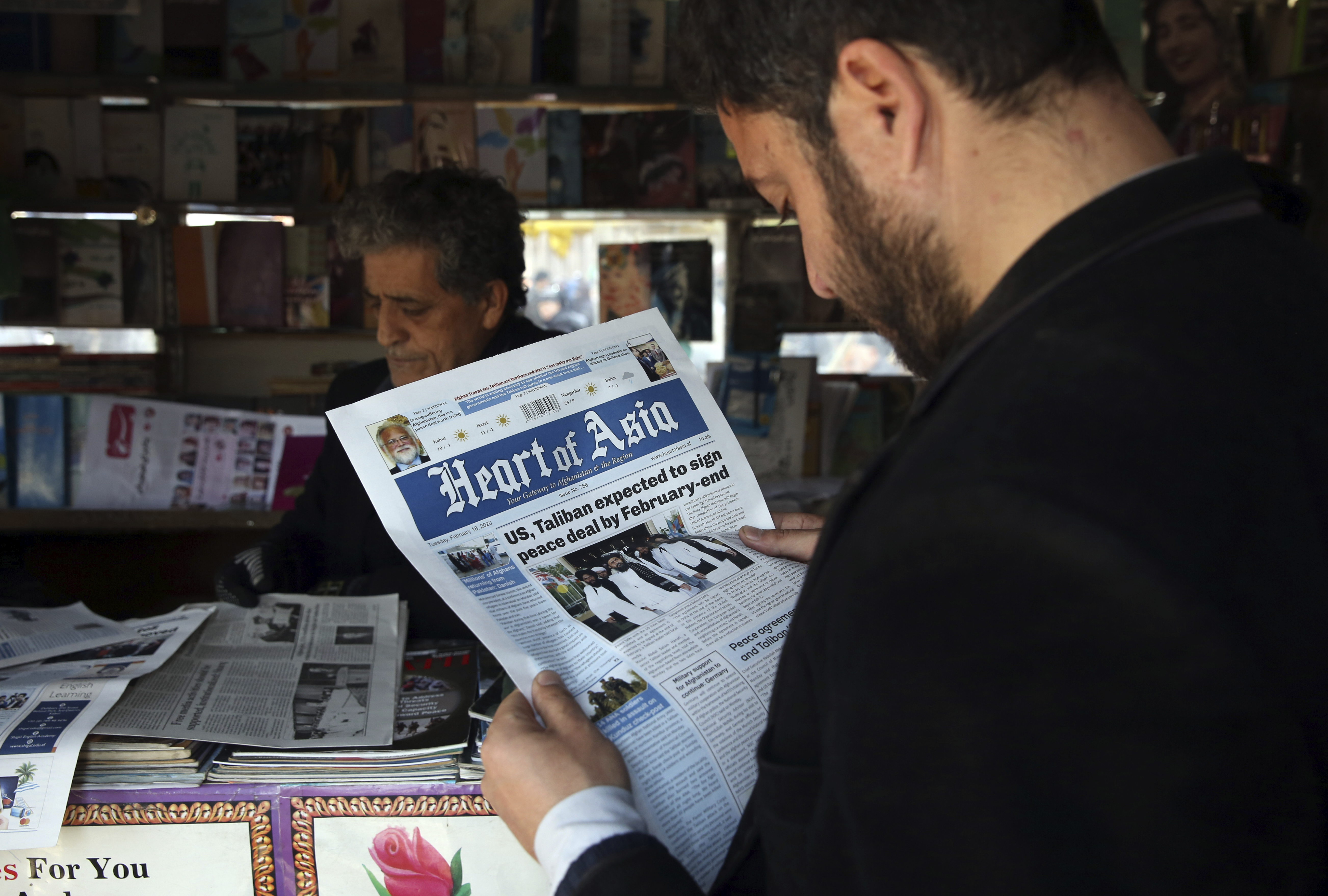 A man reads a local newspaper about peace talks in Kabul, Afghanistan. Saturday, Feb. 22, 2020. A temporary truce between the United States and the Taliban took effect on Friday, setting the stage for the two sides to sign a peace deal next week aimed at ending 18 years of war in Afghanistan and bringing U.S. troops home. (AP Photo/Rahmat Gul)