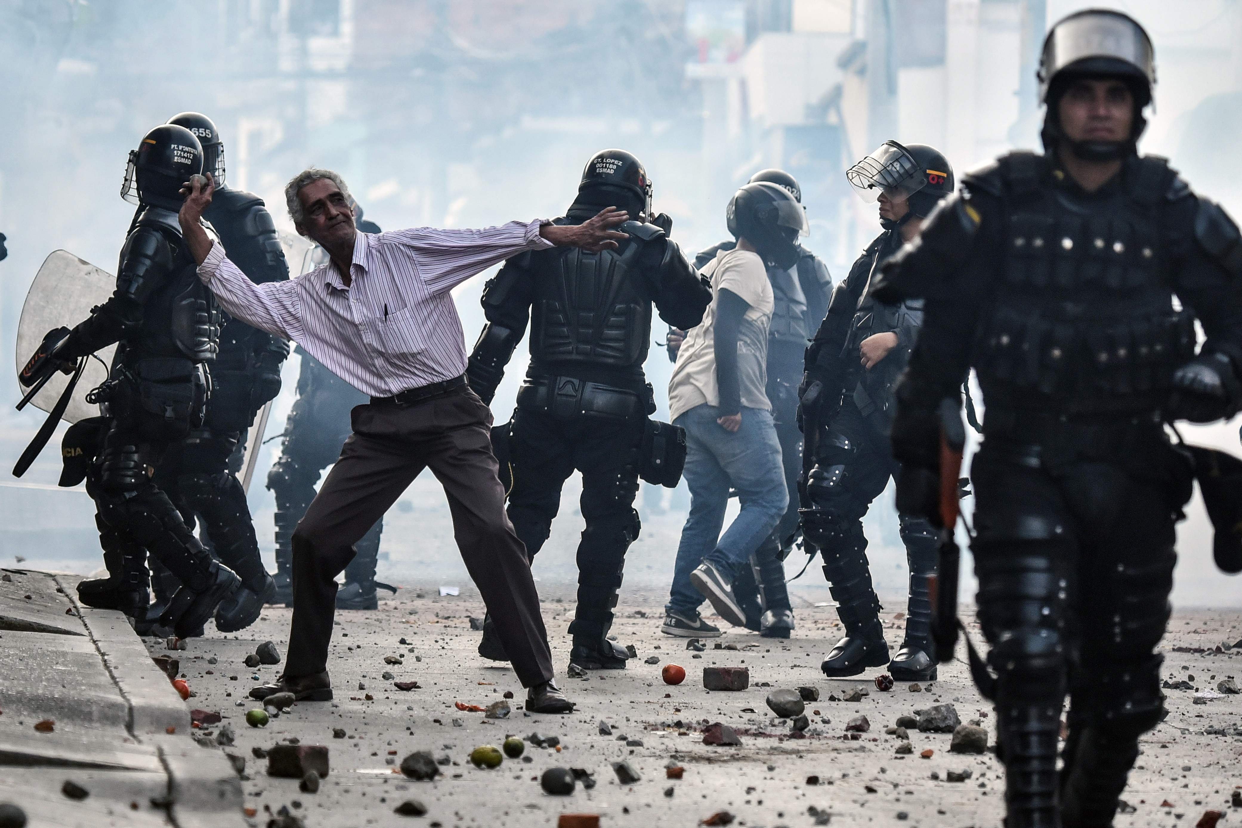 TOPSHOT - A demonstrator throws stones during a protest against a campaign rally held for Rodrigo Londono Echeverri, known as "Timochenko", the presidential candidate for the Common Alternative Revolutionary Force (FARC) political party, who was to hold a campaign meeting during his visit to the municipality of Yumbo, Colombia, on February 7, 2018 but was forced to leave because protesters were throwing stones. / AFP PHOTO / Luis ROBAYO