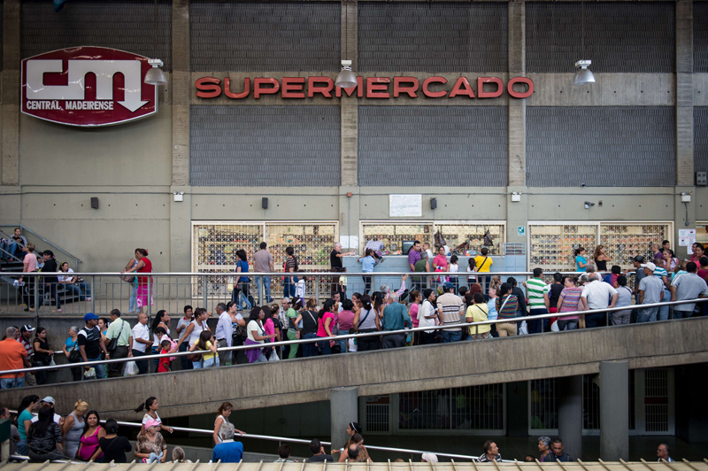 Decenas de personas hicieron fila el martes pasado en las fueras de un supermercado en Caracas. Venezuela sufre una escasez de casi un tercio de los productos básicos, la inflación se encuentra en el 63% y enfrenta una recesión económica, a causa de la sequía de divisas y la limitación de las importaciones esenciales. | AFP
