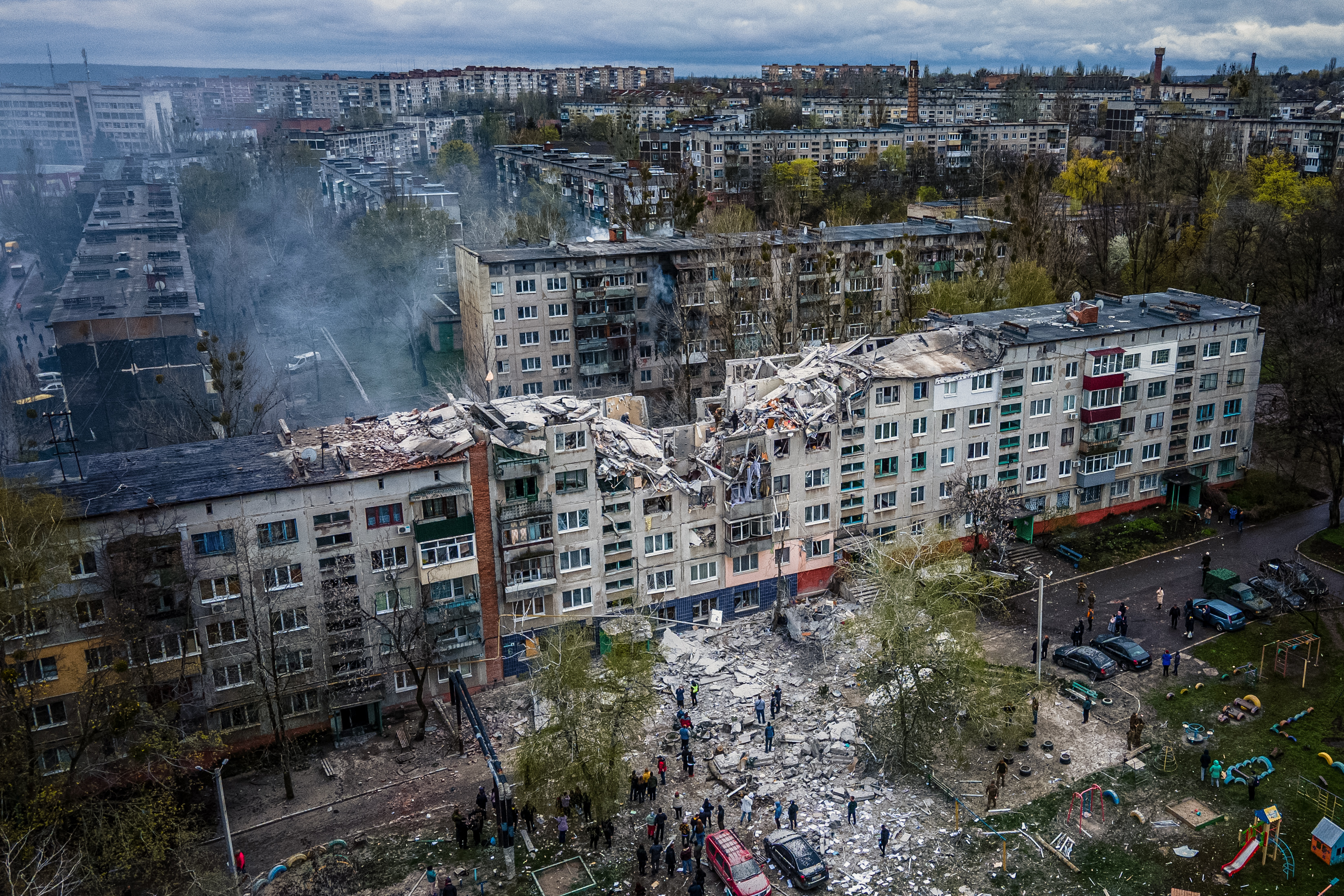 This aerial view shows rescuers on top of a partially destroyed residential building, after a shelling in Sloviansk, on April 14, 2023, amid Russia's military invasion on Ukraine. - Russian shelling of a residential building in the eastern Ukrainian city of Sloviansk killed at least five people on April 14, the local governor said, warning that others could be buried in the rubble. (Photo by Ihor TKACHOV / AFP)