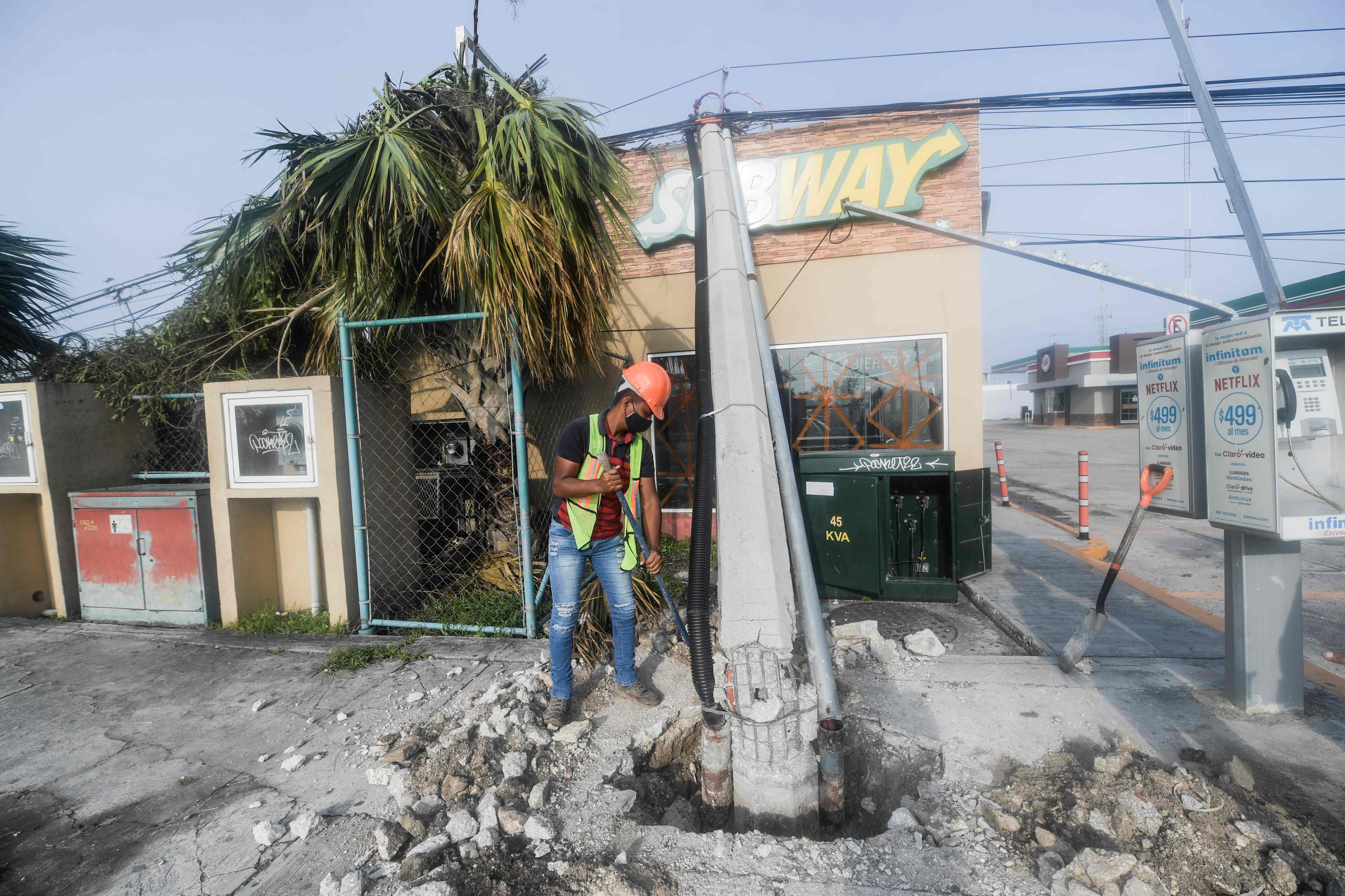 A worker repairs a street lamp post damaged by Hurricane Delta in Cancun, Quintana Roo state, Mexico, on October 8, 2020. - Hurricane Delta regained strength as it headed towards the United States early Thursday after lashing Mexico's Caribbean coast, where some tourists complained about conditions in crowded emergency shelters during a pandemic. (Photo by PEDRO PARDO / AFP)