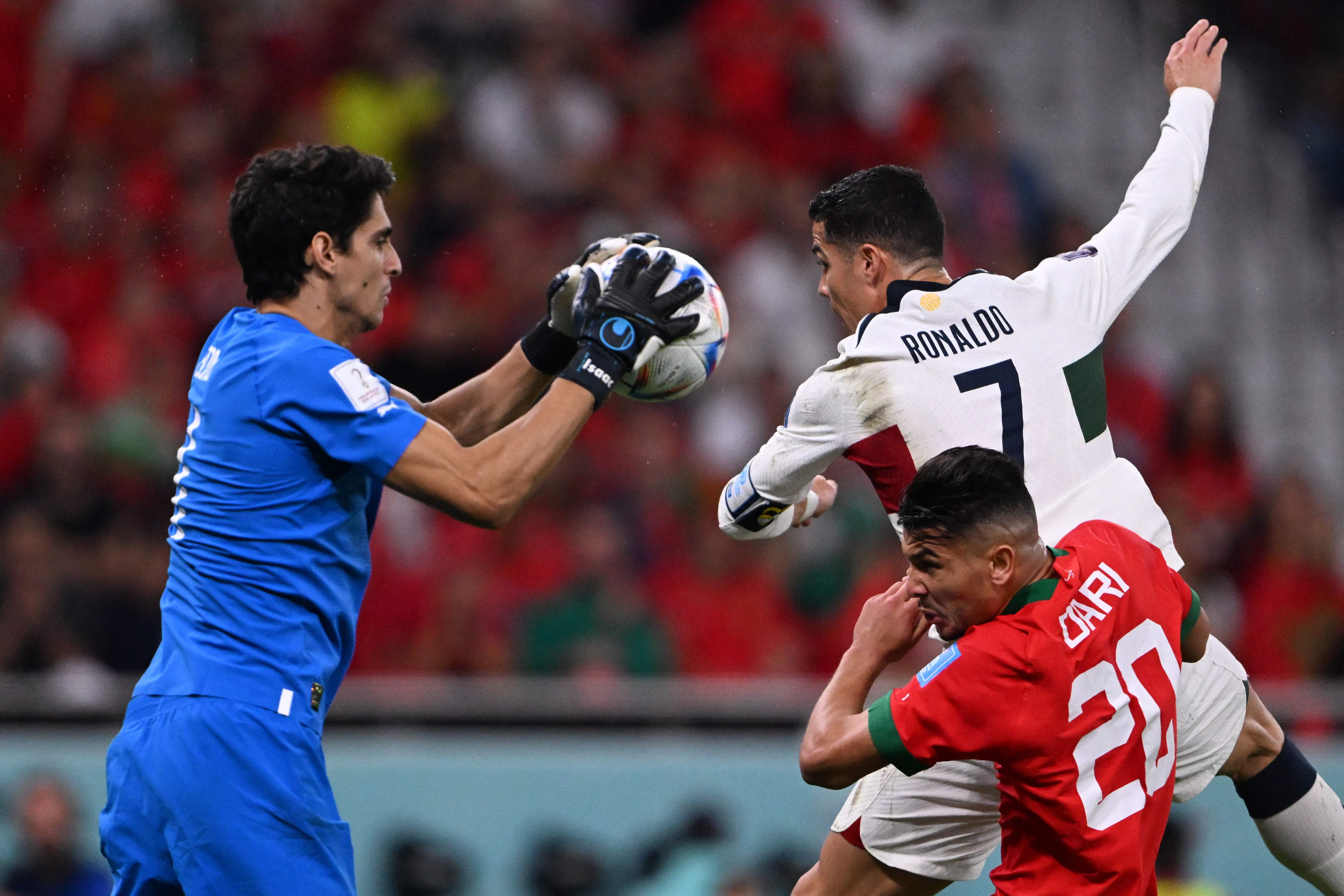 TOPSHOT - Morocco's goalkeeper #01 Yassine Bounou (L) saves a shot by Portugal's forward #07 Cristiano Ronaldo (top) next to Morocco's defender #20 Achraf Dari during the Qatar 2022 World Cup quarter-final football match between Morocco and Portugal at the Al-Thumama Stadium in Doha on December 10, 2022. (Photo by Kirill KUDRYAVTSEV / AFP)