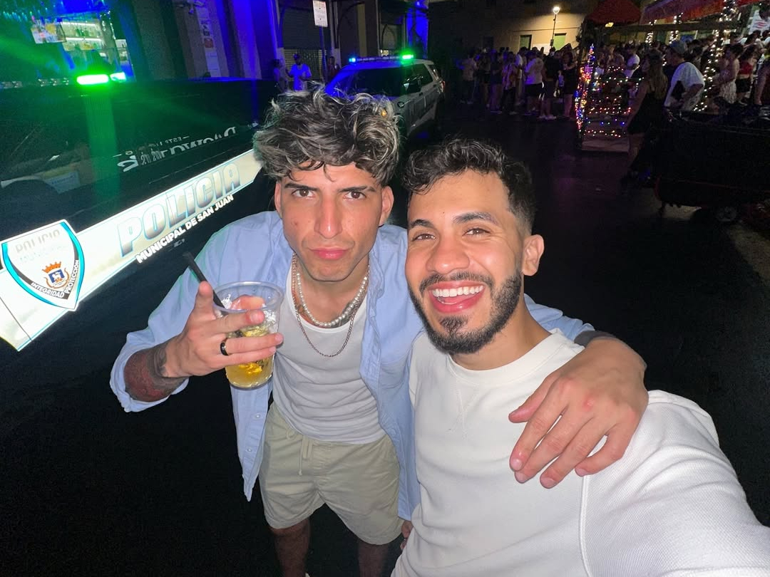 Julián Valverde a la izquierda con un vaso con una bebida alcohólica, abrazando a Araya Vlogs en un bar de Puerto Rico