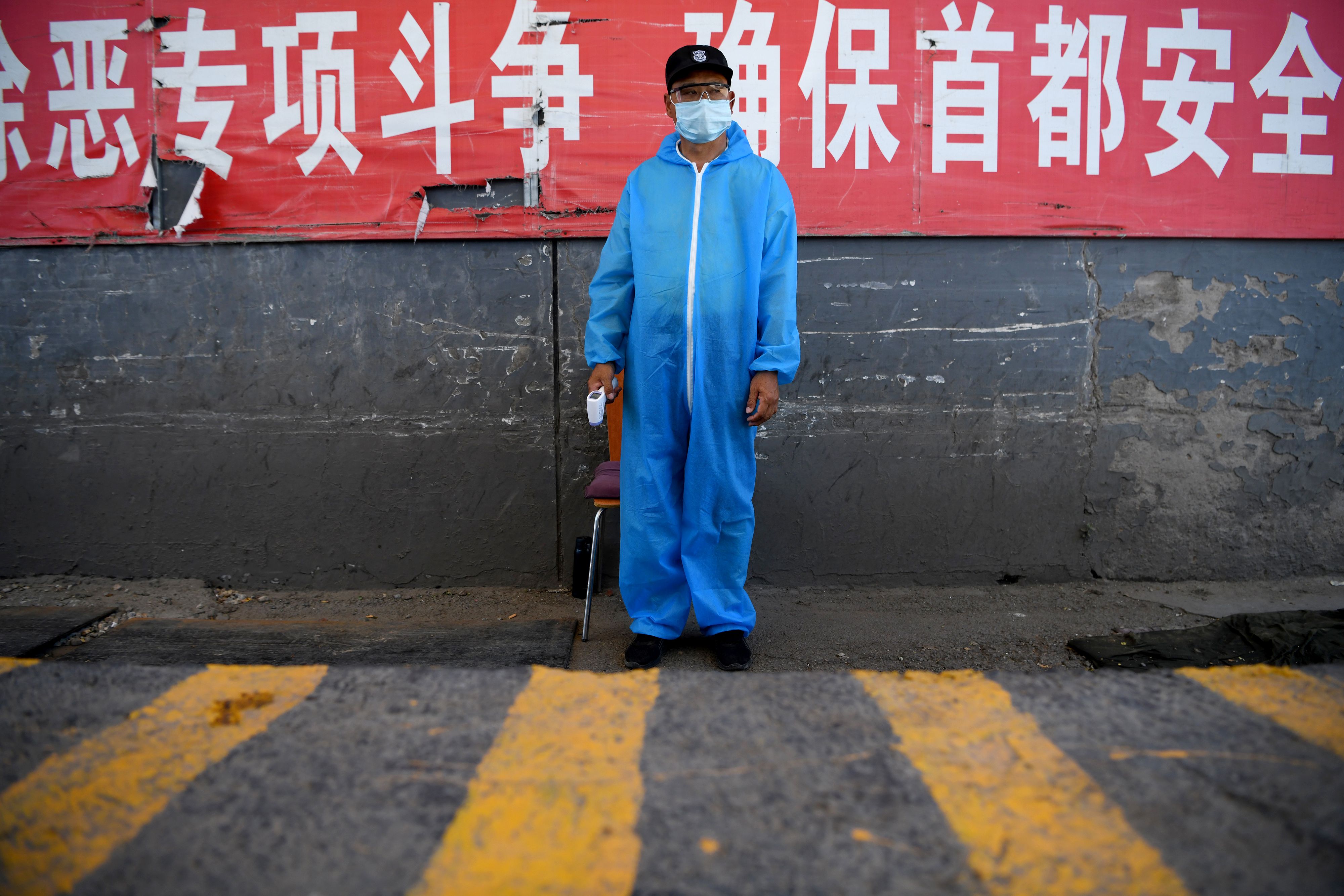 A security guard wearing a protective mask and suit stands at a checkpoint at the Xinfadi market in Beijing on June 14, 2020. - The domestic COVID-19 coronavirus outbreak in China had been brought largely under control through strict lockdowns that were imposed early this year -- but a new cluster has been linked to Xinfadi market in south Beijing. (Photo by NOEL CELIS / AFP)