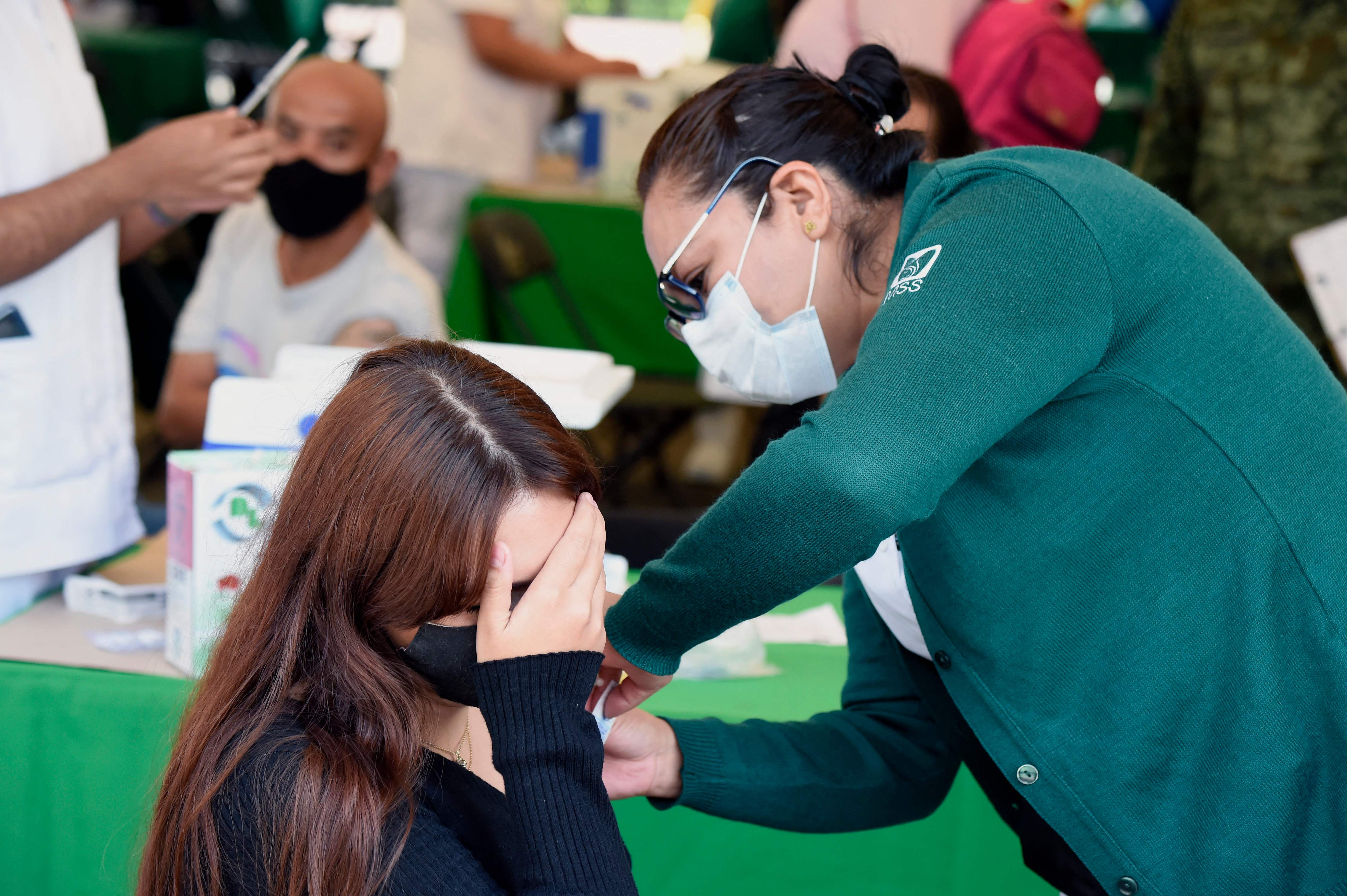 A young woman receives her first dose of the Sputnik-V vaccine against COVID-19 in Mexico City, on July 27, 2021. - Population between 18 and 29 years are receiving their first dose against the virus, as Mexico faces a third wave of COVID-19 contagions. Although the indicators of deaths and hospitalizations remain far from the January levels -when the occupancy rate was of 95% and the dead toll more than 900 deaths per day- infections have accelerated and last week, for the first time in a month, the number of deaths exceeded 300 reported in 24 hours. (Photo by ALFREDO ESTRELLA / AFP)