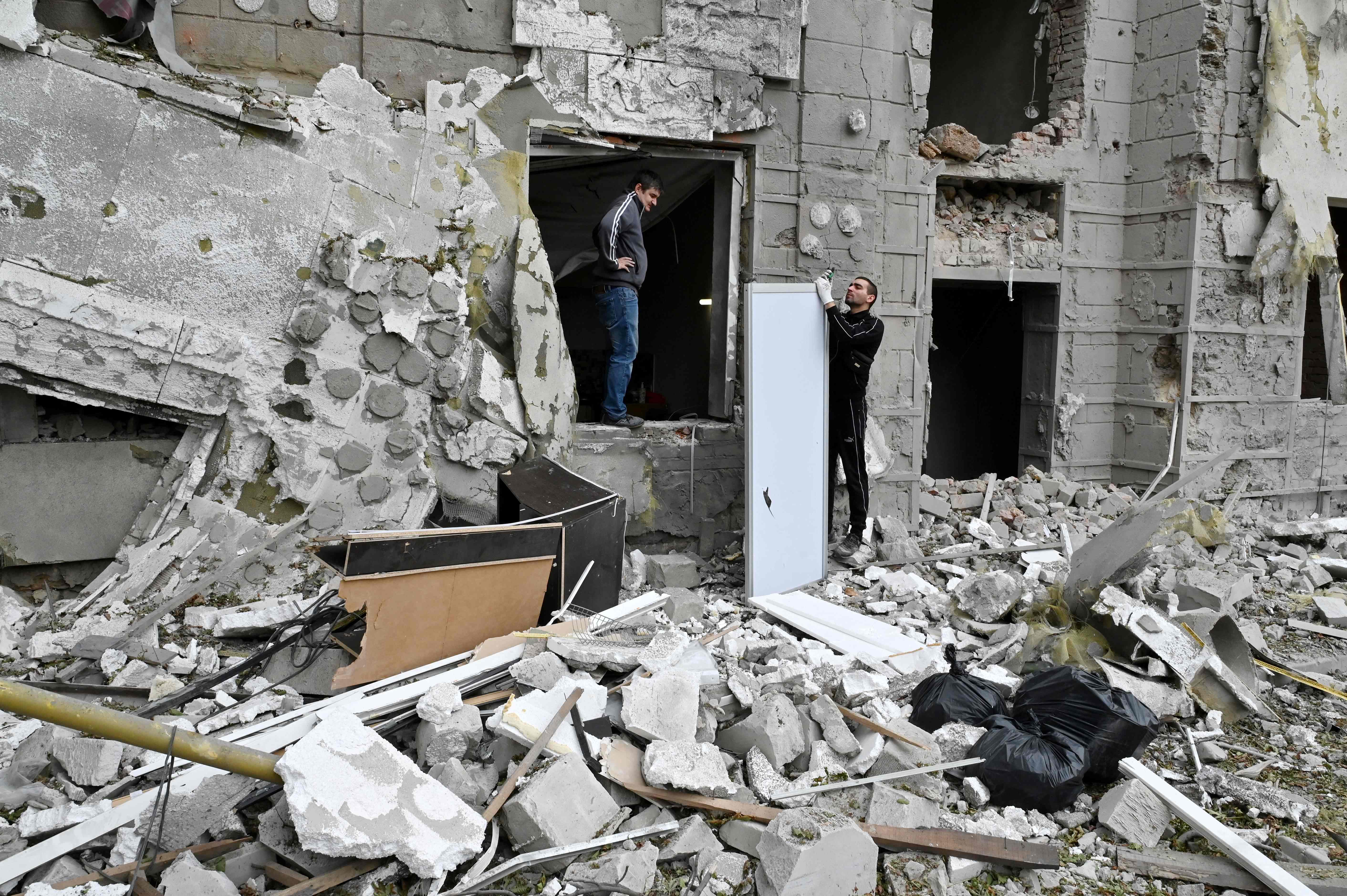 TOPSHOT - Local residents stand outside their building partially destroyed by a missile strike on Kharkiv on September 12, 2022 amid the Russian invasion of Ukraine. (Photo by SERGEY BOBOK / AFP)