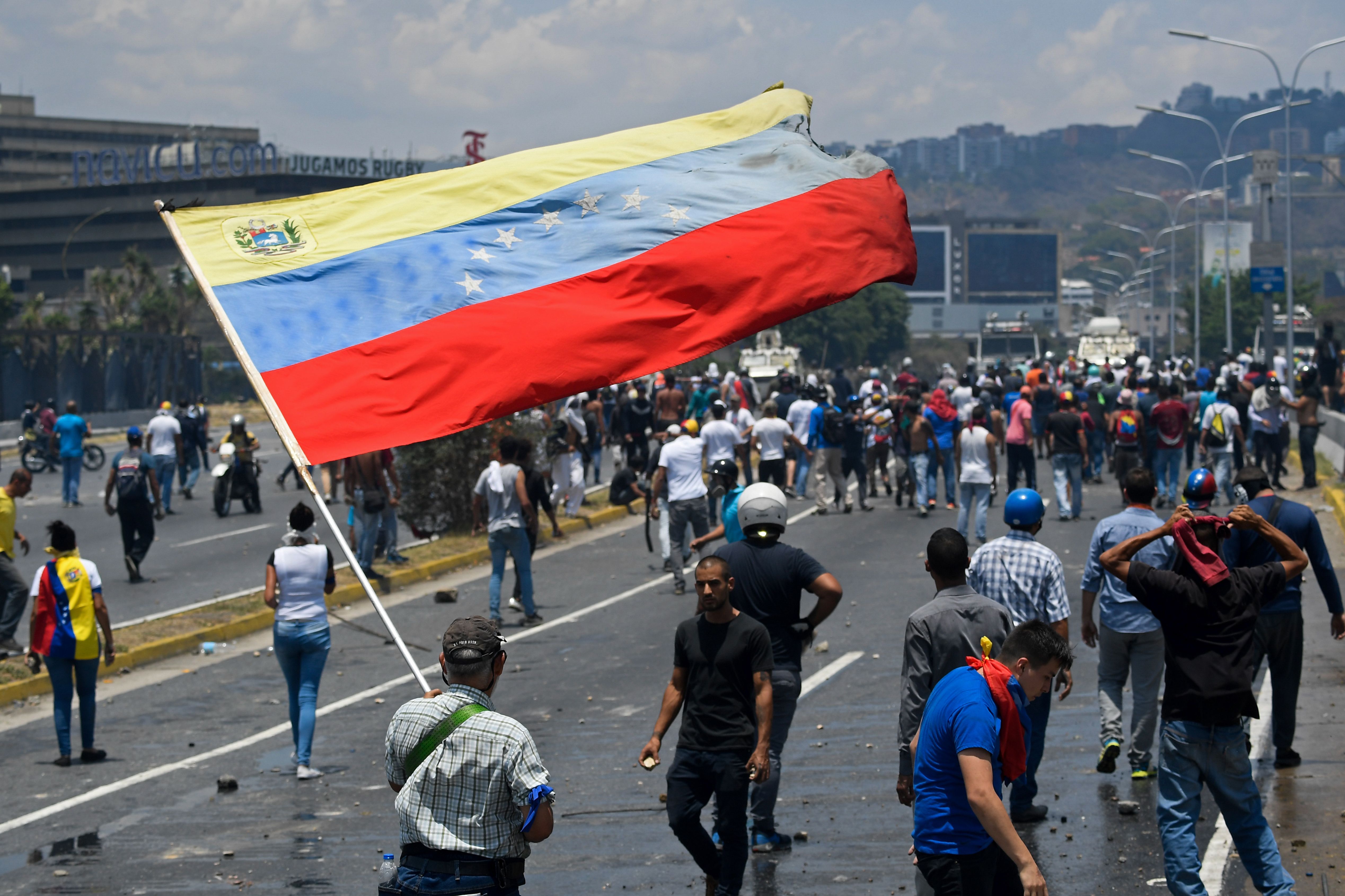 An opposition demonstrator waves a Venezuelan national flag during clashes with soldiers loyal to Venezuelan President Nicolas Maduro after troops joined opposition leader Juan Guaido in his campaign to oust Maduro's government, in the surroundings of La Carlota military base in Caracas on April 30, 2019. - Guaido -- accused by the government of attempting a coup Tuesday -- said there was "no turning back" in his attempt to oust President Nicolas Maduro from power. (Photo by Federico PARRA / AFP)