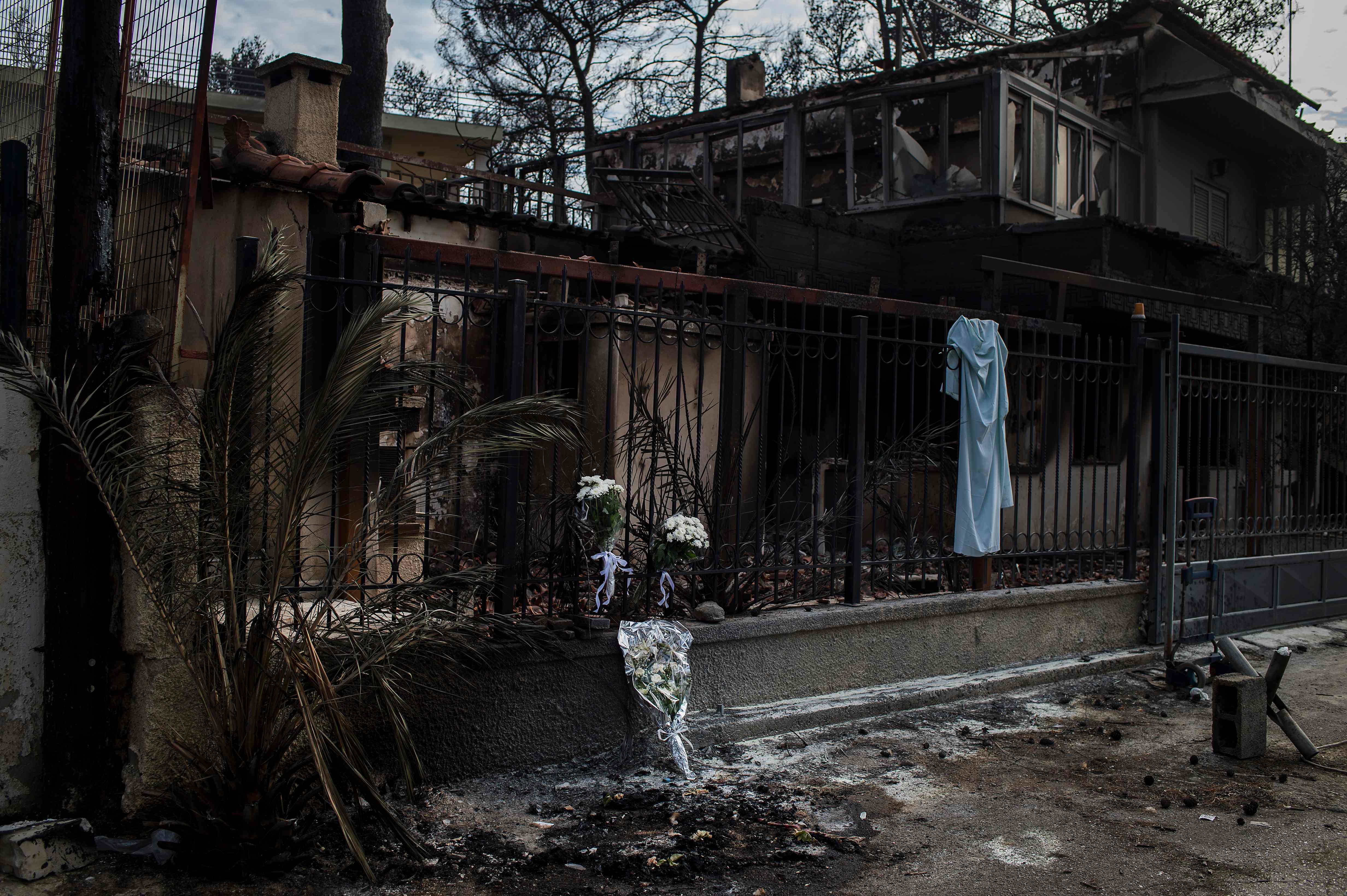 A picture taken on July 26, 2018 shows flowers on a fence of a house where two bodies where found following a wildfire at the village of Neos Voutzas, near Athens.
Greece was counting the cost on July 26 of its deadliest wildfires in living memory, as emergency crews searched incinerated homes and vehicles for the missing after at least 81 people were confirmed to have died. / AFP PHOTO / ANGELOS TZORTZINIS