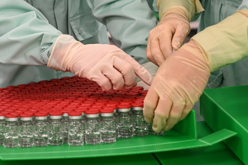 Laboratory technicians handle capped vials as part of filling and packaging tests for the large-scale production and supply of the University of Oxford�s COVID-19 vaccine candidate, AZD1222, conducted on a high-performance aseptic vial filling line on September 11, 2020 at the Italian biologics� manufacturing facility of multinational corporation Catalent in Anagni, southeast of Rome, during the COVID-19 infection, caused by the novel coronavirus. - Catalent Biologics� manufacturing facility in Anagni, Italy will serve as the launch facility for the large-scale production and supply of the University of Oxford�s Covid-19 vaccine candidate, AZD1222, providing large-scale vial filling and packaging to British-Swedish multinational pharmaceutical and biopharmaceutical company AstraZeneca. (Photo by Vincenzo PINTO / AFP)