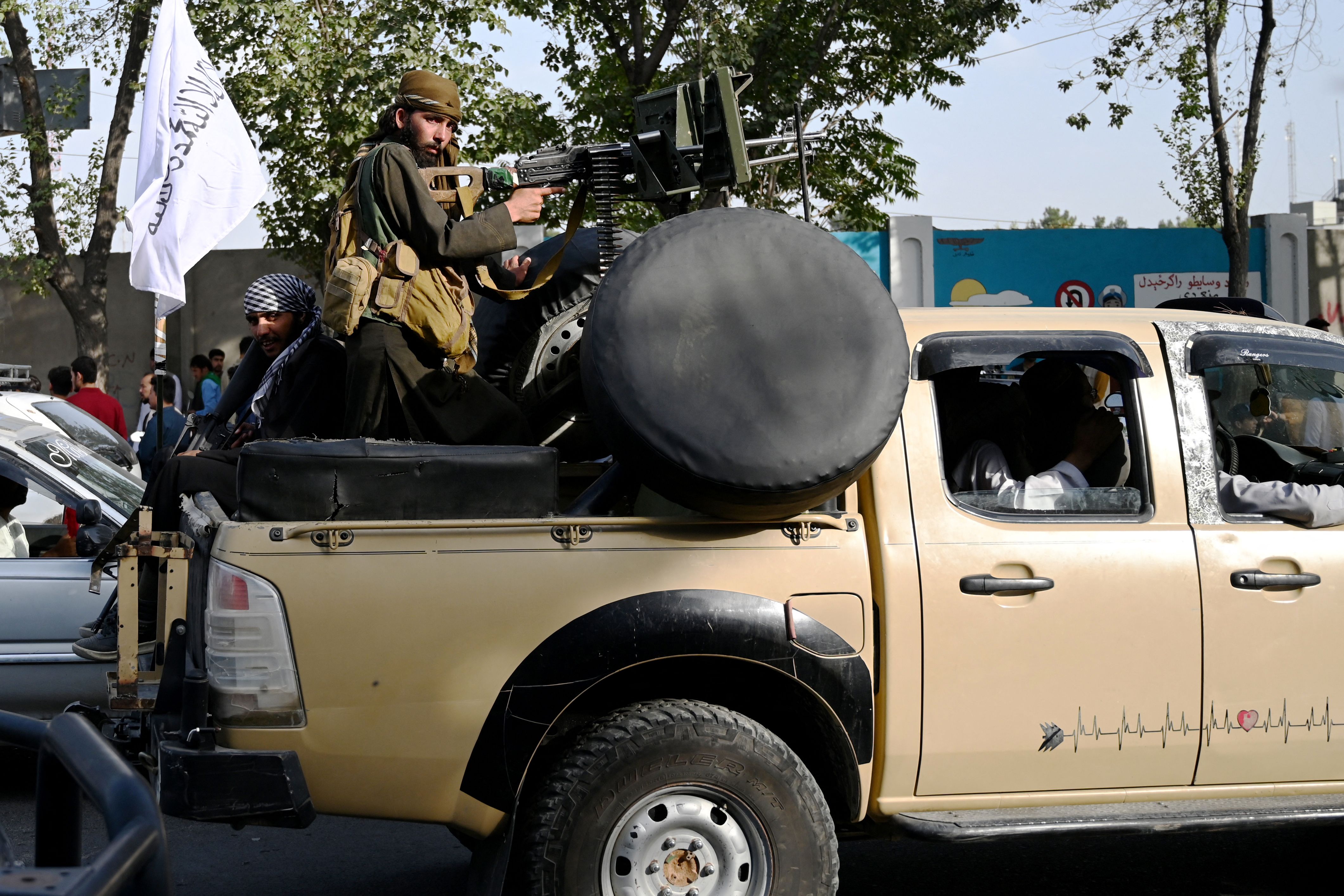 Taliban fighters travel with weapons mounted on a vehicle in Kabul on August 19, 2021 after Taliban's military takeover of Afghanistan. (Photo by WAKIL KOHSAR / AFP)