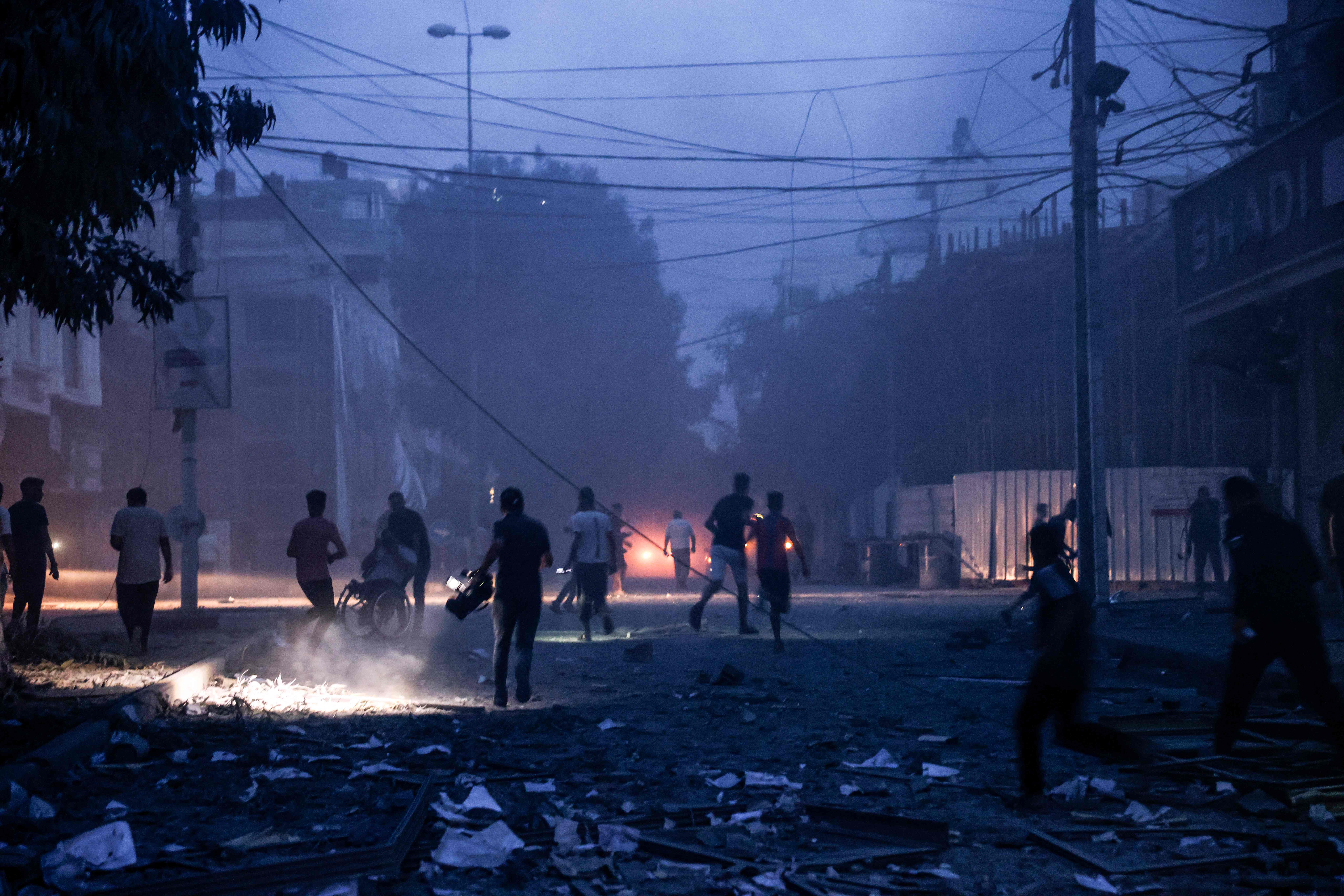 EDITORS NOTE: Graphic content / People run along a debris-strewn street following Israeli air strikes in Gaza City on October 7, 2023. Palestinian militants have begun a "war" against Israel which they infiltrated by air, sea and land from the blockaded Gaza Strip, Israeli officials said, a major escalation in the Israeli-Palestinian conflict. (Photo by Mohammed ABED / AFP)