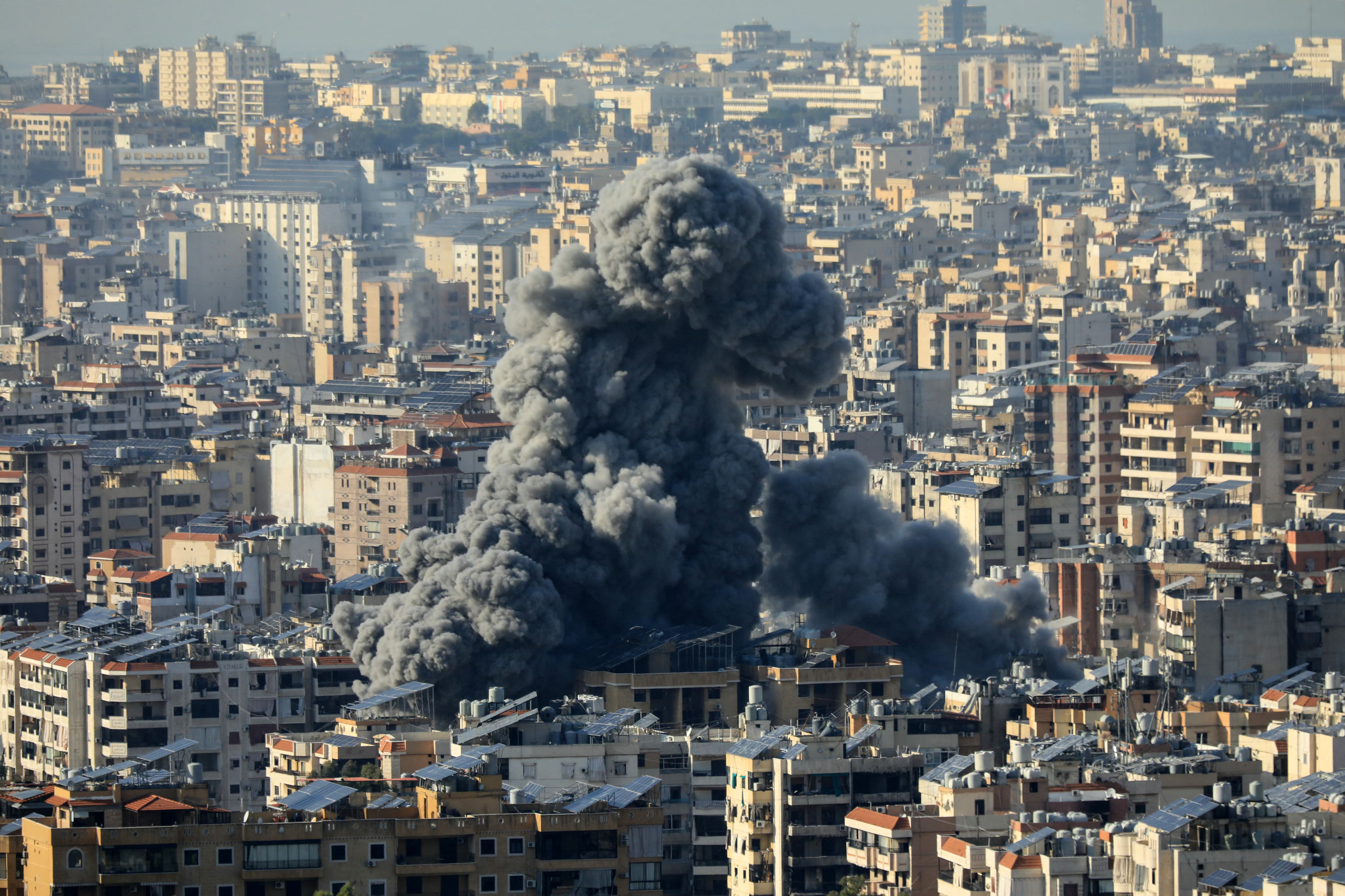 Columna de humo denso elevándose entre edificios de Beirut tras bombardeos israelíes que han causado múltiples muertes.