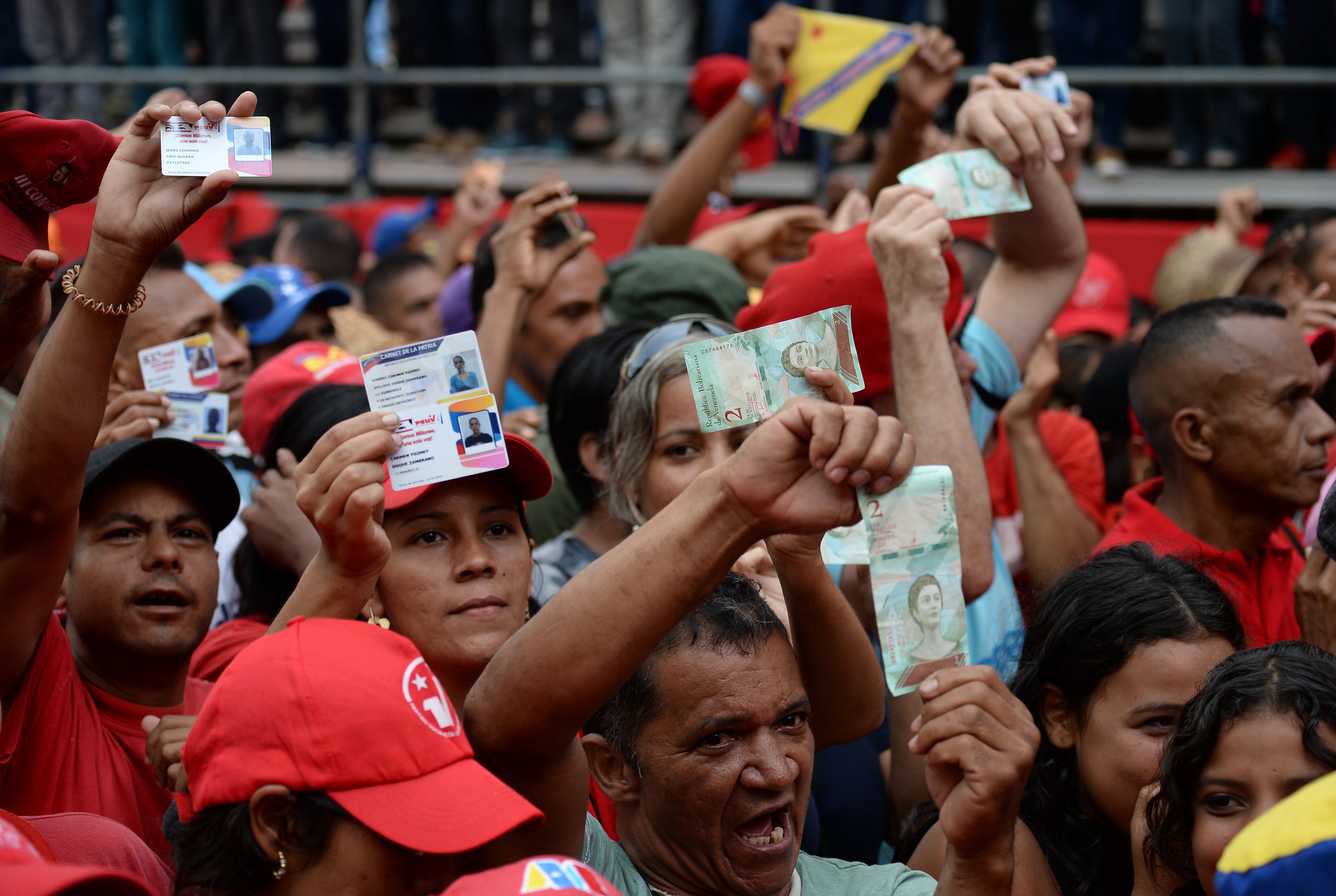People rally in support of the economic measures taken by Venezuelan President Nicolas Maduro, in Caracas on August 21, 2018. - Venezuela's government devalued the bolivar by 96 percent on Tuesday under a new exchange rate announced by the central bank as it desperately tried to steer a way out of its economic crisis. The announcement comes a day after new banknotes stripped of five zeroes entered circulation as part of a radical plan by President Nicolas Maduro to curb hyperinflation, though business leaders criticized the move as counterproductive. (Photo by Federico PARRA / AFP)
