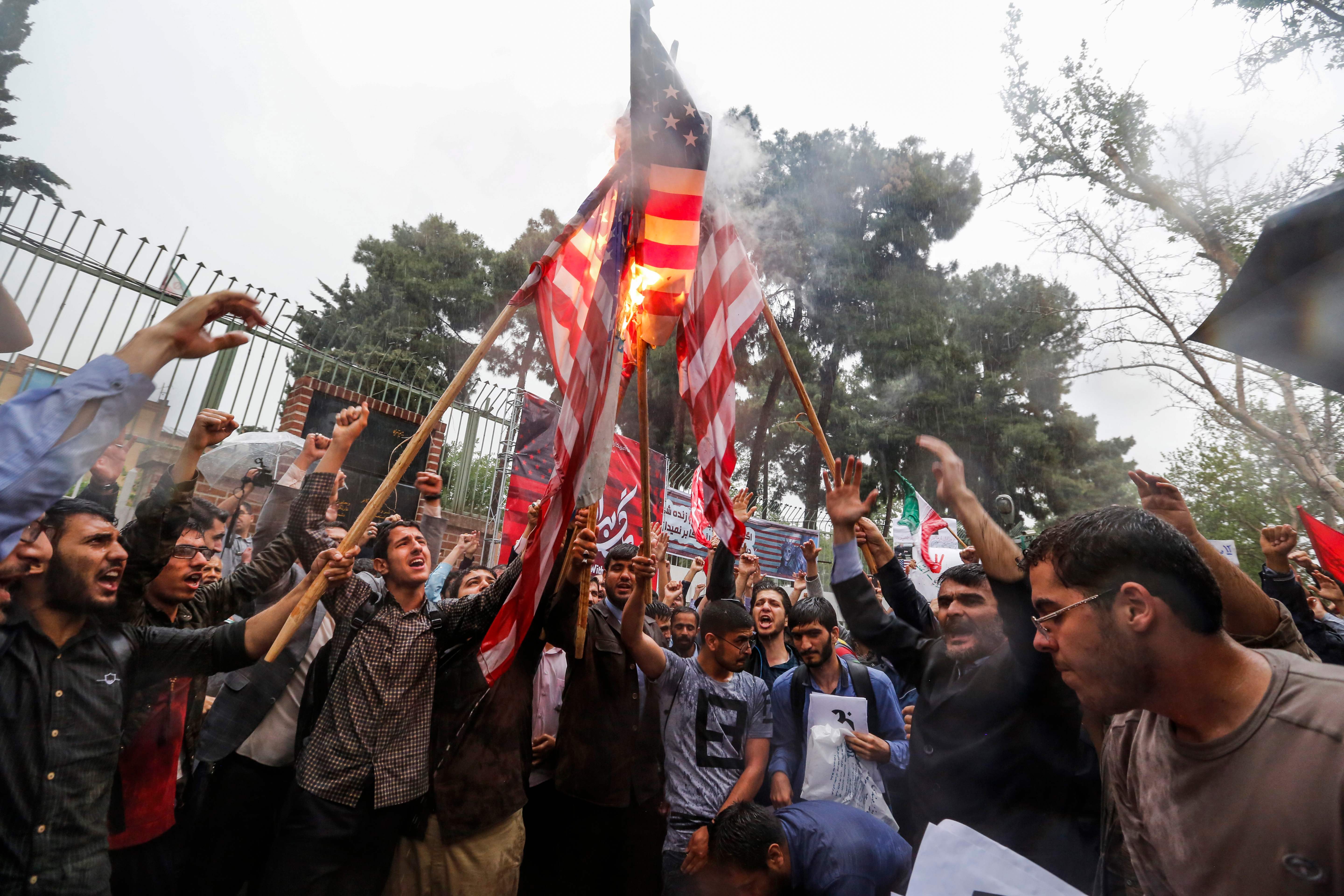 Iranians burn US flags during an anti-US demonstration outside the former US embassy headquarters in the capital Tehran on May 9, 2018.
Iranians reacted with a mix of sadness, resignation and defiance on May 9 to US President Donald Trump's withdrawal from the nuclear deal, with sharp divisions among officials on how best to respond.
For many, Trump's decision on Tuesday to pull out of the landmark nuclear deal marked the final death knell for the hope created when it was signed in 2015 that Iran might finally escape decades of isolation and US hostility. / AFP PHOTO / ATTA KENARE
