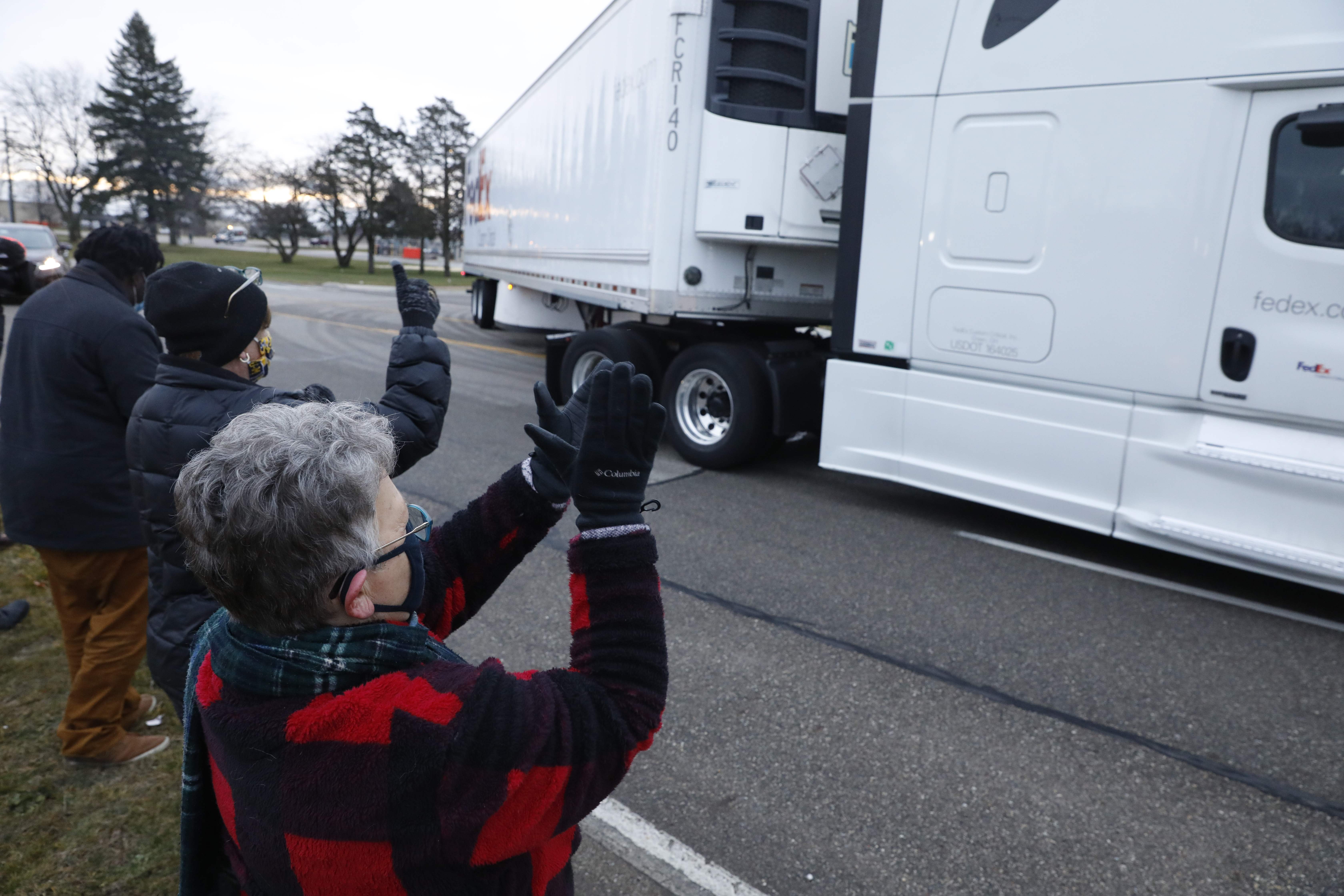 Nancy Galloway (L) and Susan Deur cheer as trucks carrying the first shipment of the Covid-19 vaccine that is being escorted by the US Marshals Service, leave Pfizer's Global Supply facility in Kalamazoo, Michigan on December 13, 2020. - The Pfizer-BioNTech Covid-19 vaccine was to begin leaving the company's Michigan factory on Sunday, ready to be injected into the arms of millions of the most vulnerable Americans as the global death toll topped 1.6 million. (Photo by JEFF KOWALSKY / AFP)
