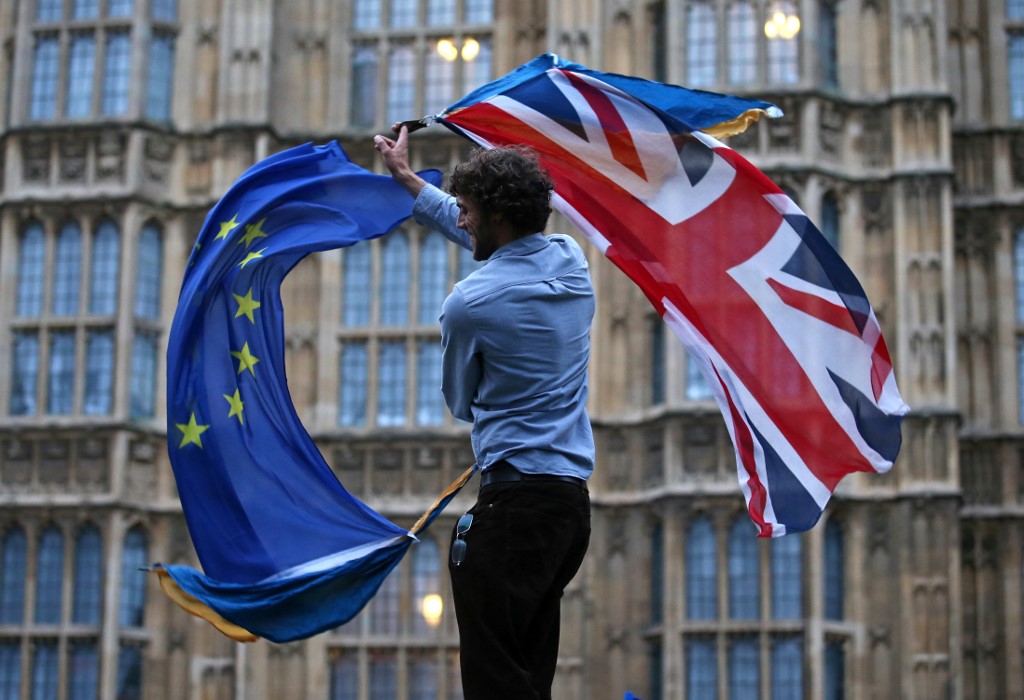 (FILES) In this file photograph taken on June 28, 2016, a man waves both a Union flag and a European flag together on College Green during an anti-Brexit protest outside The Houses of Parliament in central London. - The 27 EU member states gave the green light on December 28, 2020, for the post-Brexit trade deal to go into effect on January 1,2021, a spokesman said. Ambassadors from EU capitals met in Brussels to nod through the accord, using a procedure which will take effect at 3:00 pm (1400 GMT) on December 29. (Photo by JUSTIN TALLIS / AFP)