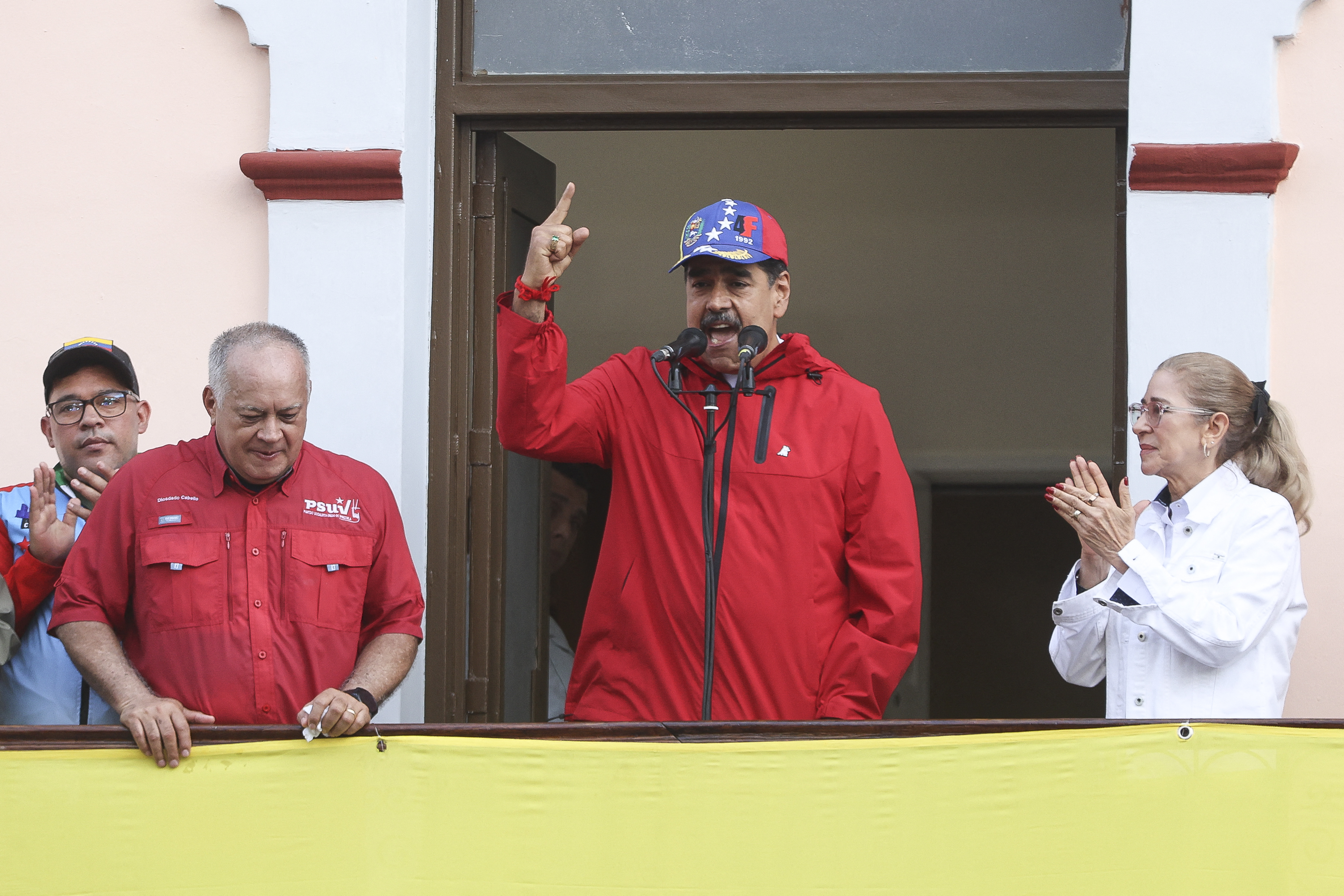 El presidente de Venezuela, Nicolás Maduro (centro), ante una multitud flanqueado por su ministro del Interior, Diosdado Cabello (izq.), y su esposa, Cilia Flores, durante una manifestación para conmemorar el aniversario del fin de la dictadura de Marcos Pérez Jiménez, quien fue derrocado tras un levantamiento popular en 1958, en Caracas, el 23 de enero del año pasado. Fotografía: