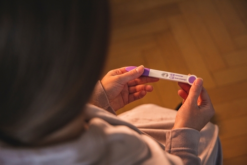 Manos de una joven sosteniendo una prueba de embarazo positiva, representando el impacto del embarazo adolescente.