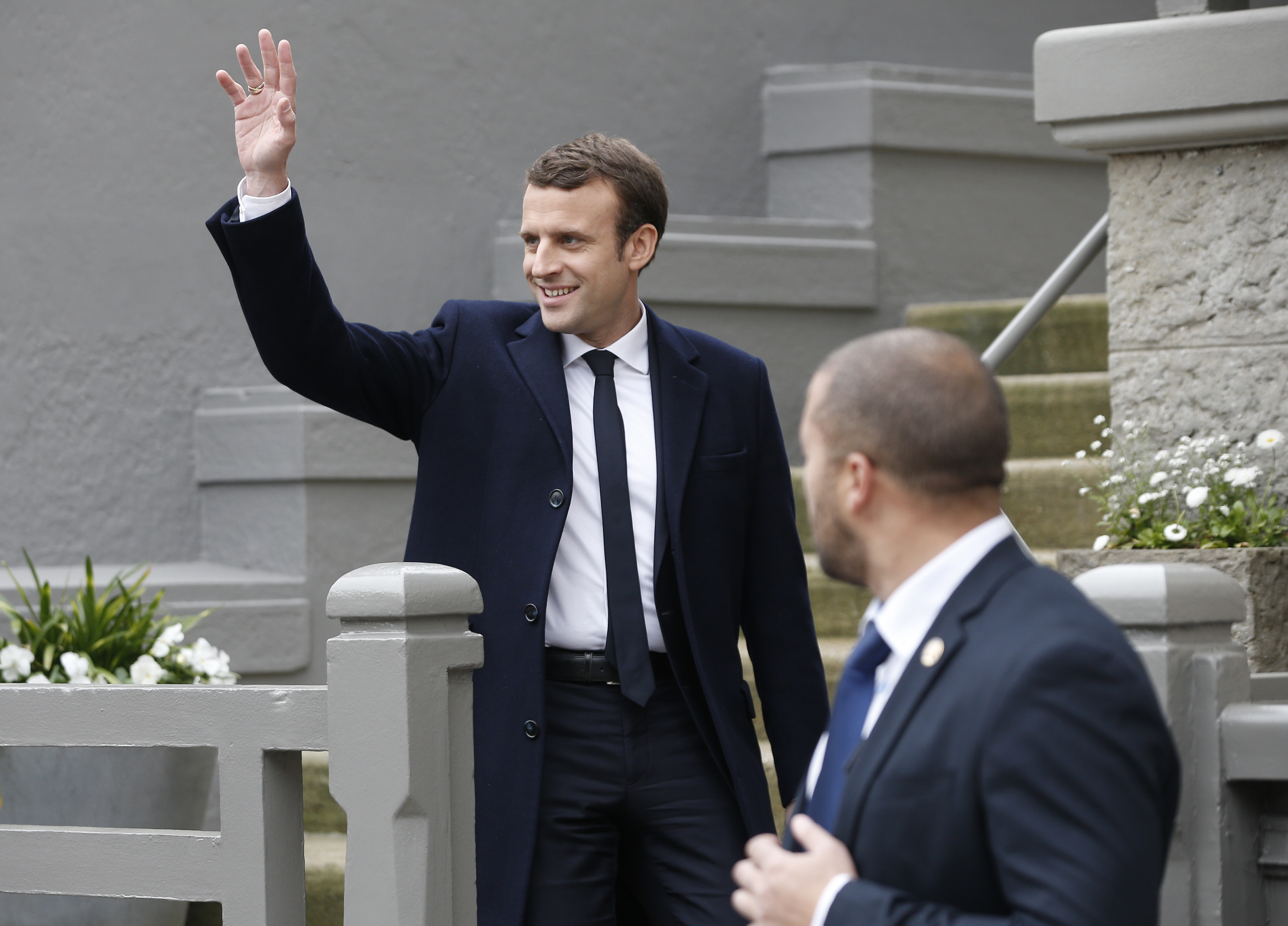 Un guardaespaldas observa cómo el candidato centrista Emmanuel Macron abandona su casa después de votar en la primera vuelta de las elecciones presidenciales francesas.