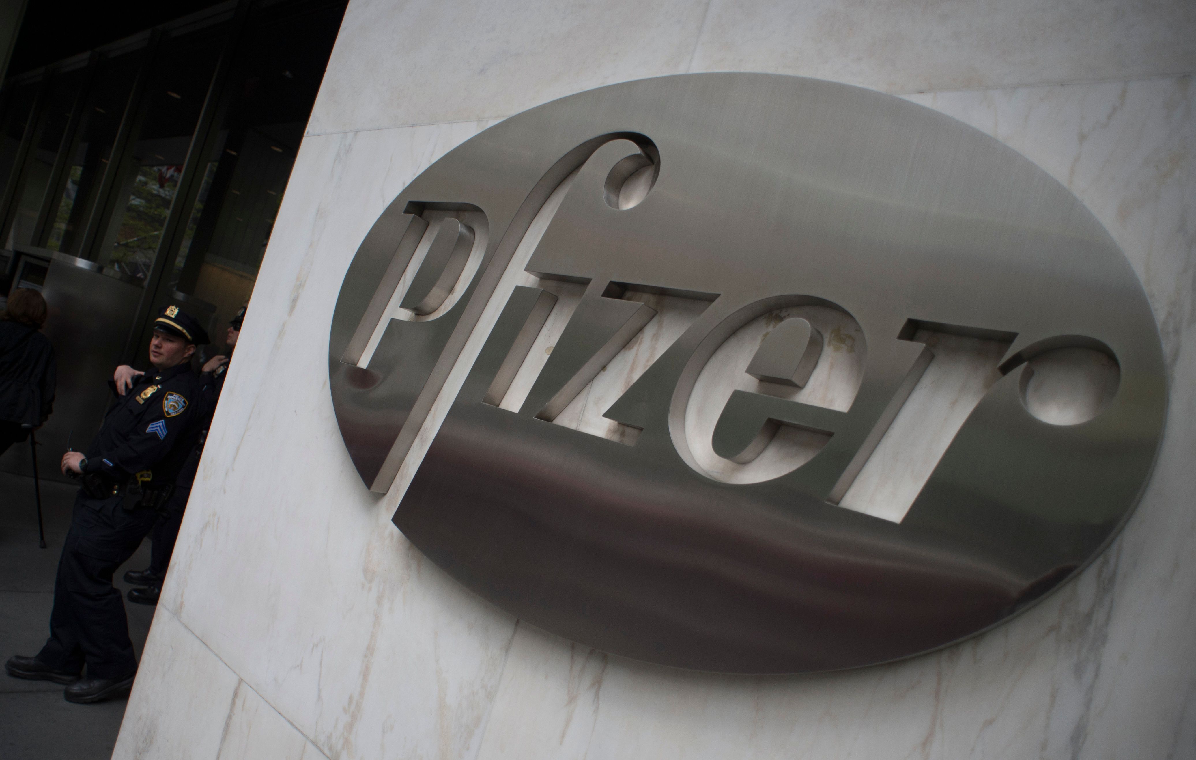 (FILES) In this file photo taken on April 27, 2016, a New York City police officer stands guard as protesters from Doctors without Borders rally in front of Pfizer�s headquarters in New York. - US pharmaceutical giant Pfizer expects to file for emergency use authorization for its Covid-19 vaccine in late November, around two weeks after the November 3 US presidential election, it said on October 16, 2020. The company said it hopes to move ahead with the vaccine after safety data is available in the third week of November, immediately lifting the company's shares two percent in the US. (Photo by Don EMMERT / AFP)