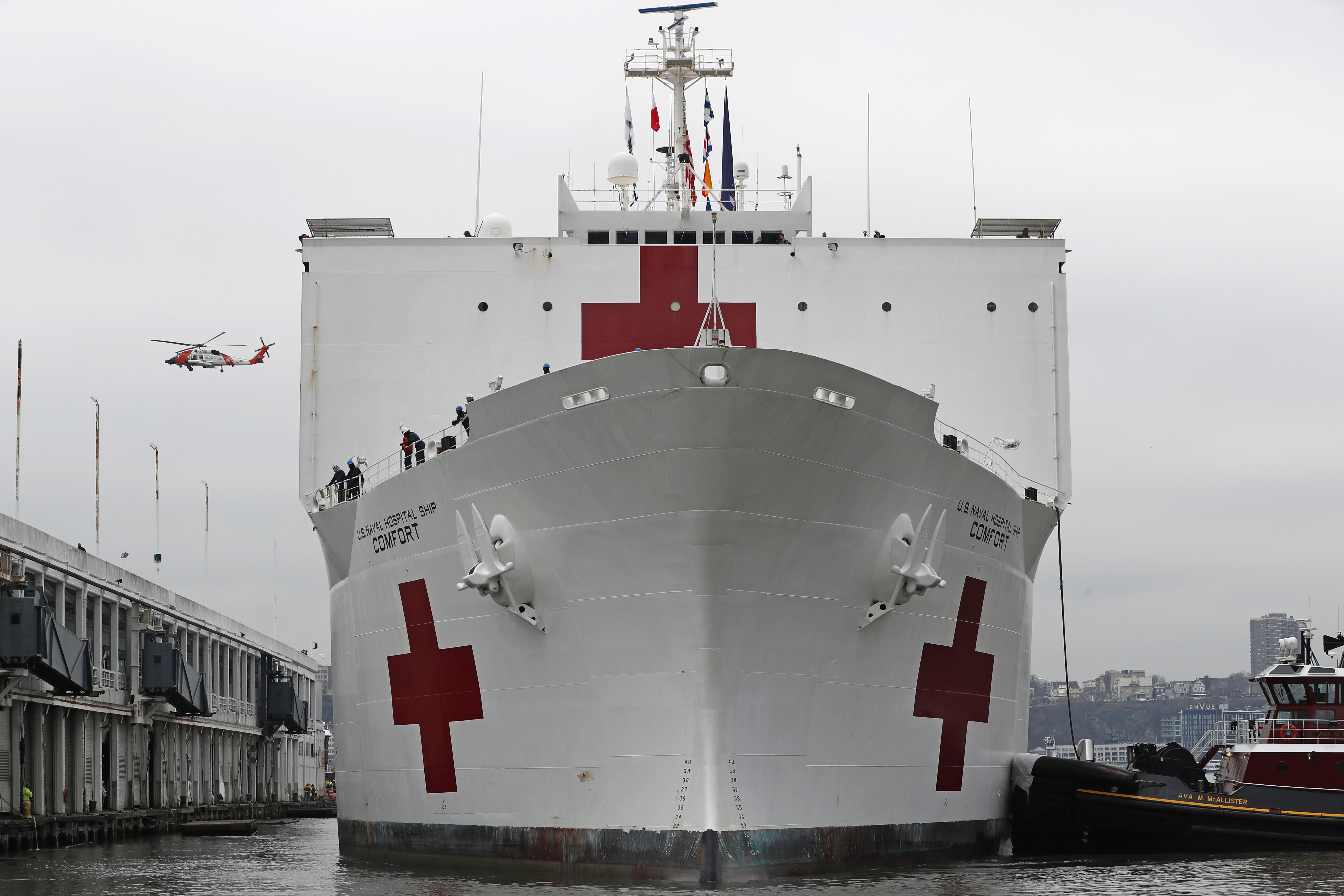 A U.S. Coast Guard helicopter flies overhead as the USNS Comfort, a naval hospital ship with a 1,000 bed-capacity, docks at Pier 90, Monday, March 30, 2020, in New York. The ship will be used to treat New Yorkers who don't have coronavirus as land-based hospitals fill up with and treat those who do. (AP Photo/Kathy Willens)