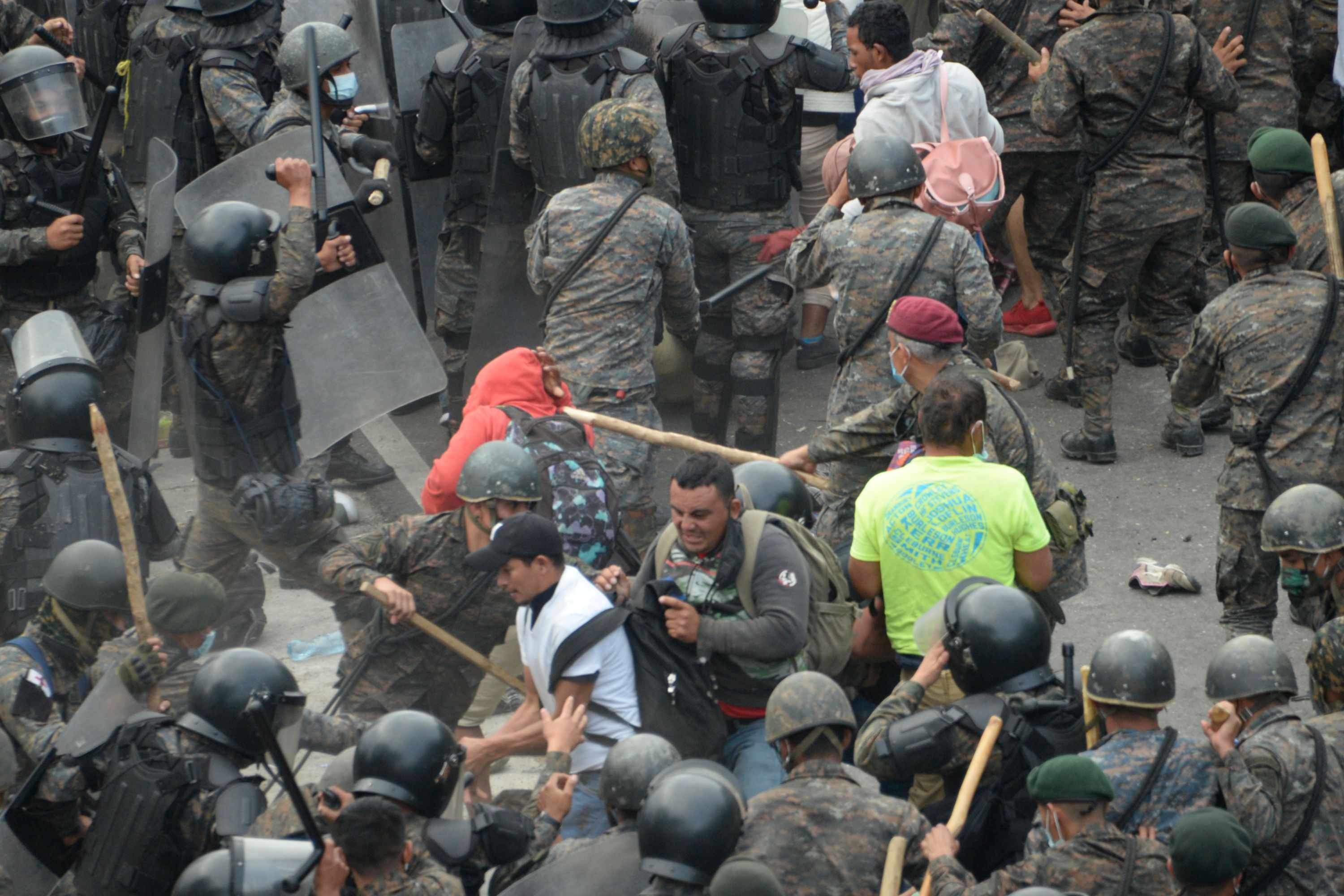 TOPSHOT - Honduran migrants, part of a caravan heading to the United States, clash with Guatemalan security forces in Vado Hondo, Guatemala on January 17, 2021. - Guatemalan police fired tear gas Sunday to try to disperse a caravan of thousands of migrants heading toward the United States. (Photo by Johan ORDONEZ / AFP)
