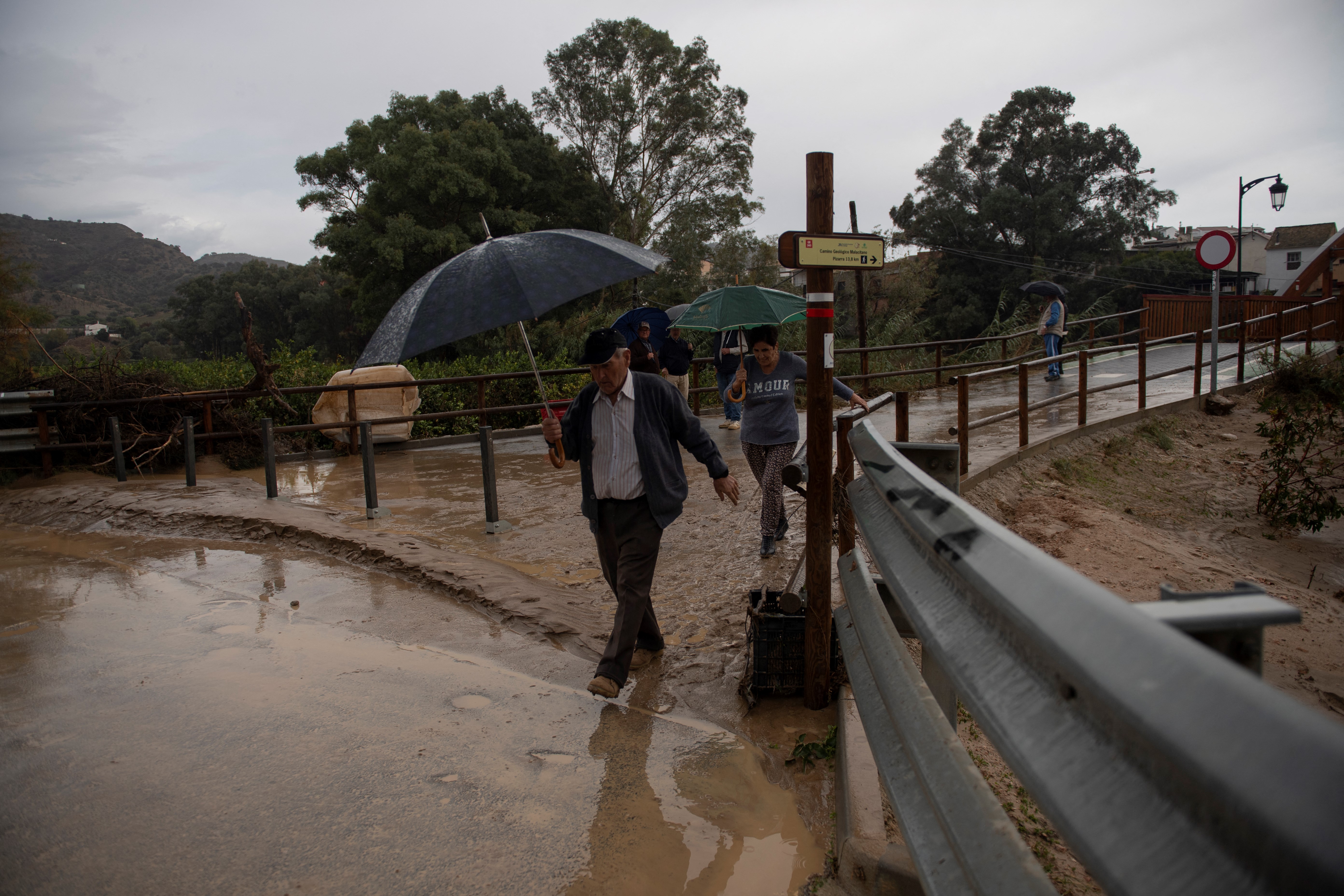 Los peatones, protegidos por una sombrilla, caminan por una calle inundada en Álora, cerca de MálagaLos peatones, protegidos por una sombrilla, caminan por una calle inundada en Álora, cerca de Málaga.