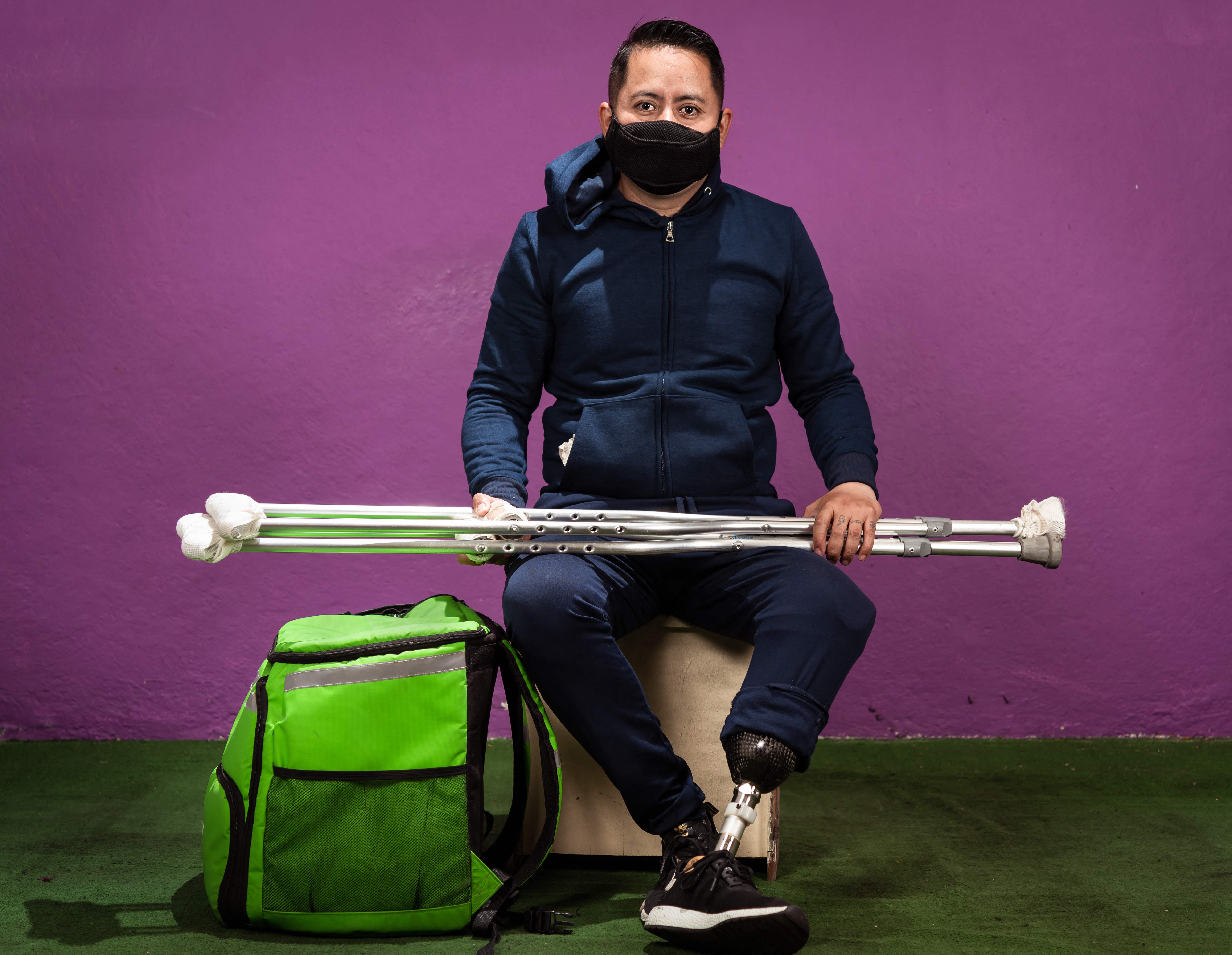 Victor Manuel Kim, a member of the @ninunrepartidormenos (Not a delivery worker less) collective of men and women delivery workers, who have suffered abuse, accidents or harassment by customers, poses for a photograph in Mexico City, on November 17, 2021. - Kim was run over by a vehicle while making home deliveries and lost part of his left leg due to the accident. He continues to deliver with a prosthetic leg. (Photo by Omar TORRES / AFP)