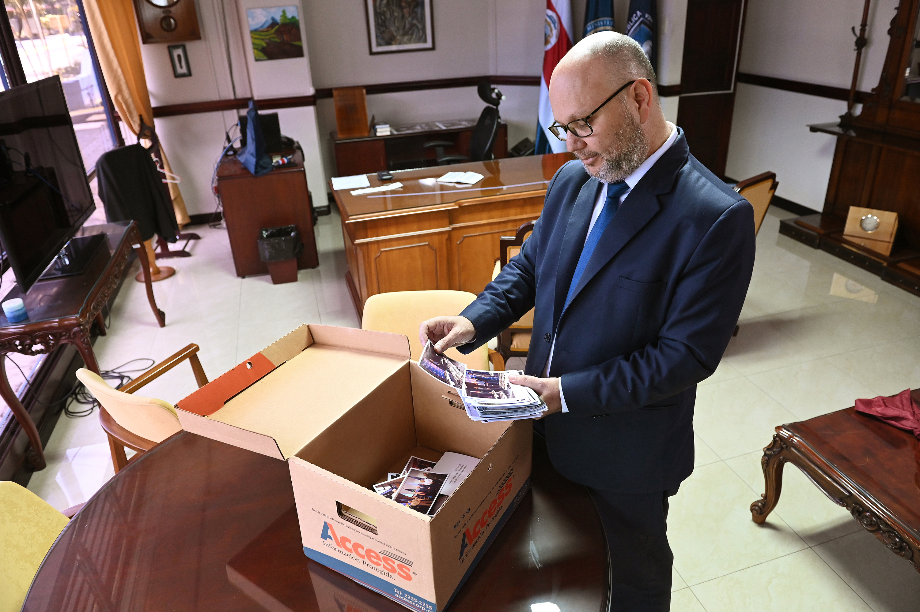 28 de abril del 2022. Ministerio de Seguridad. Retratos al ministro de Seguridad Michael Soto quién finaliza su gestión a cargo de esa cartera de gobierno. Documental fotográfico del proceso de transición del ministro actual al próximo ministro. En la foto: Michael Soto guarda fotografías en una caja en su oficina ésta mañana.. Foto: Albert Marín para la Nación.