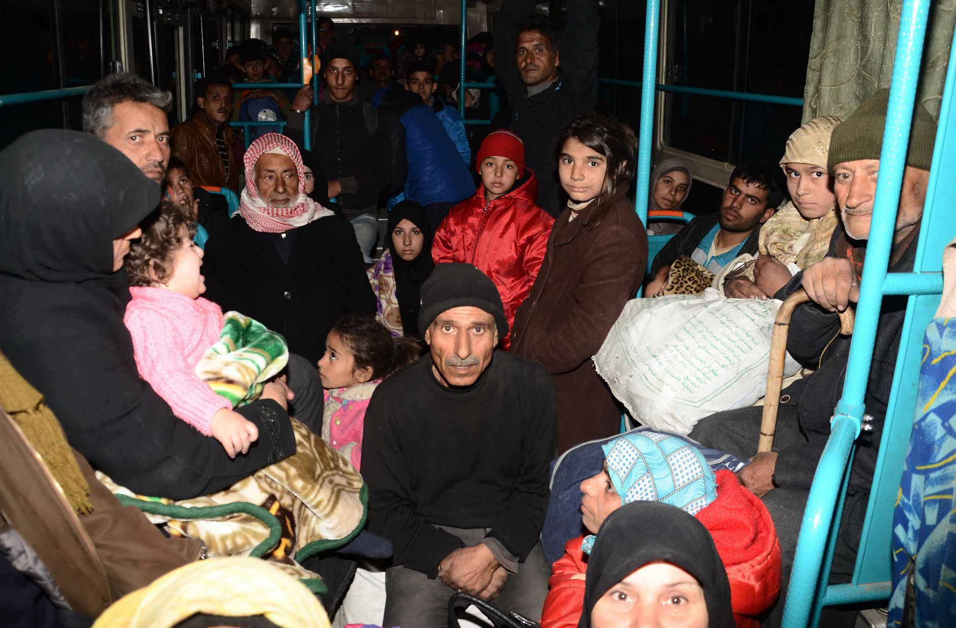 familias sirias, de varios distritos orientales de Alepo, son evacuadas en autobús el 27 de noviembre al Sheikh Maqsud, un enclave controlado por los kurdos.