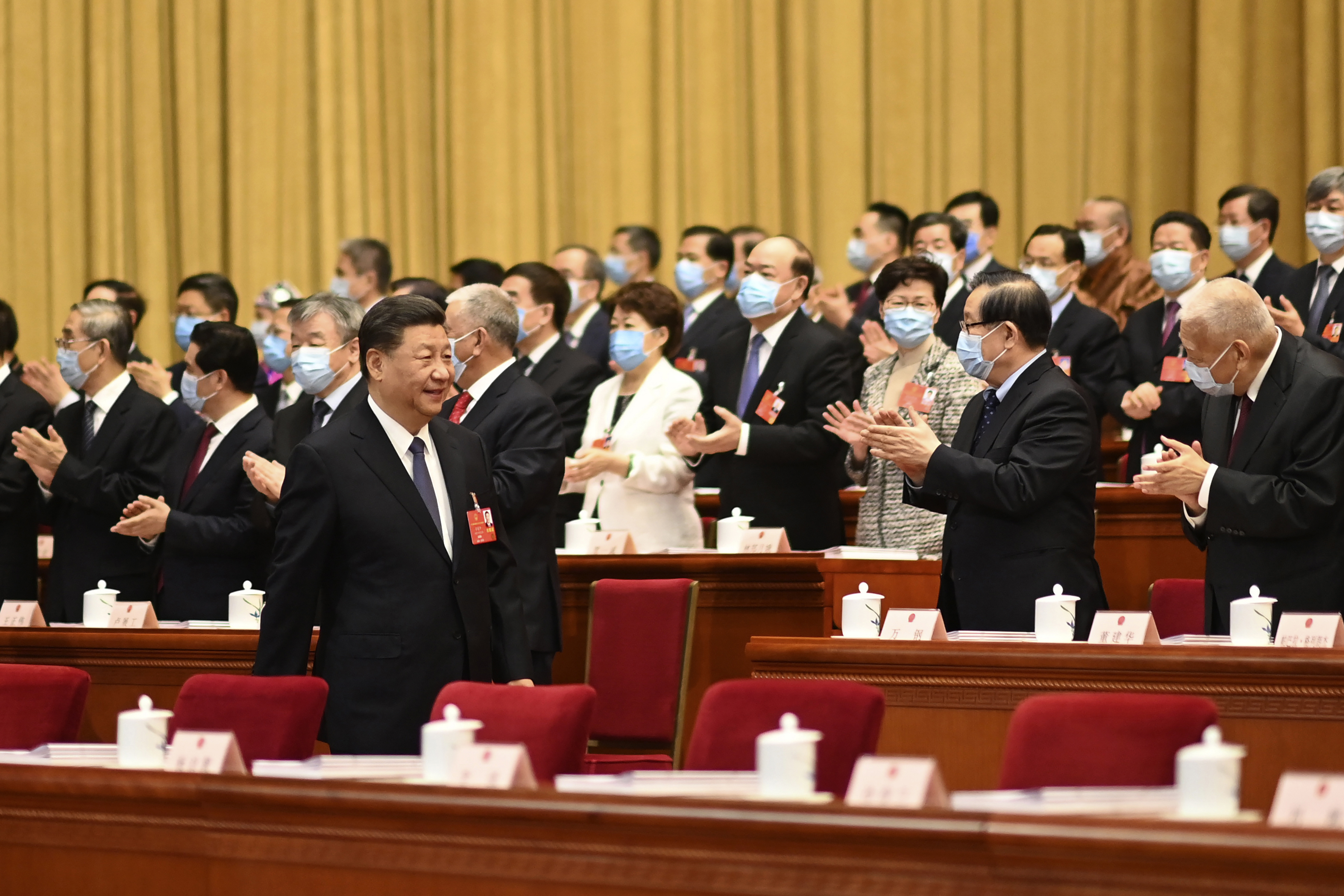 In this photo released by Xinhua News Agency, delegates applaud as Chinese President Xi Jinping arrives for the opening session of China's National People's Congress (NPC) at the Great Hall of the People in Beijing, Friday, May 22, 2020. (Li Xueren/Xinhua via AP)