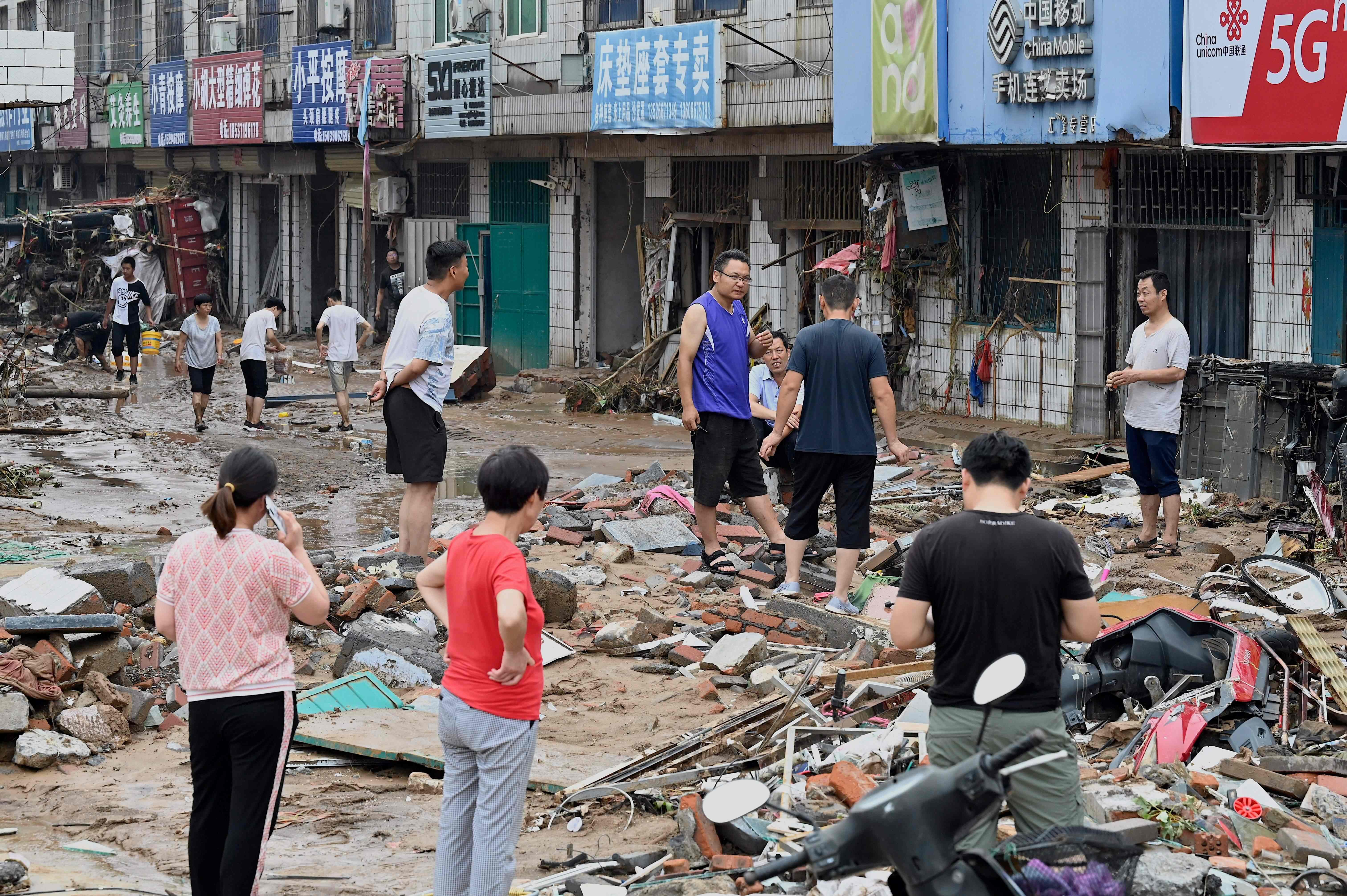 Residents chat on a muddy street after severe flooding and landslide in recent days have hit the county-level Gongyi city, near Zhengzhou, in central China�s Henan province on July 22, 2021. (Photo by JADE GAO / AFP)