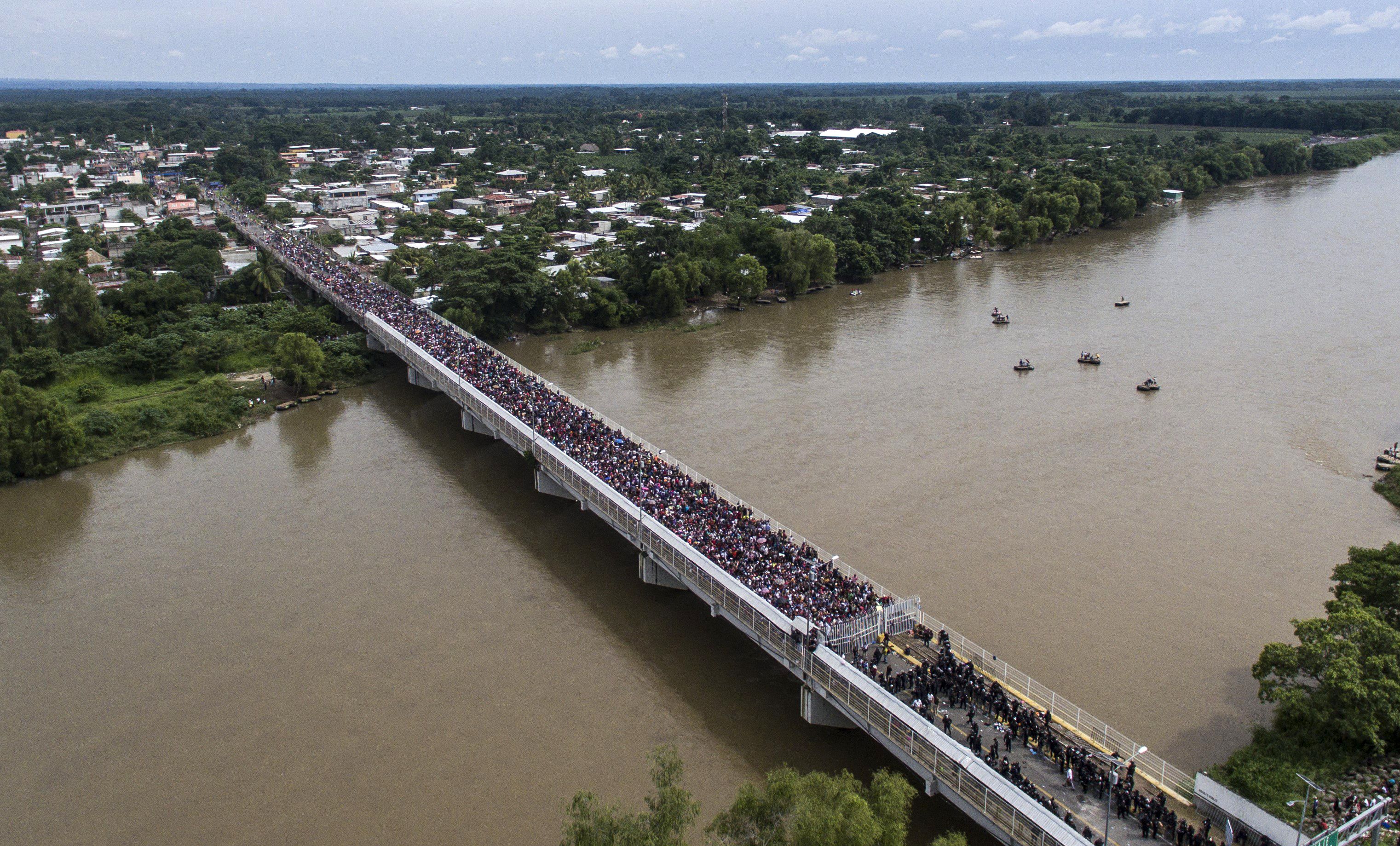 Aerial view of a Honduran migrant caravan heading to the US, as it is stopped at a border barrier on the Guatemala-Mexico international bridge in Ciudad Hidalgo, Chiapas state, Mexico, on October 19, 2018. - Honduran migrants who have made their way through Central America were gathering at Guatemala's northern border with Mexico on Friday, despite President Donald Trump's threat to deploy the military to stop them entering the United States. (Photo by PEDRO PARDO / AFP)